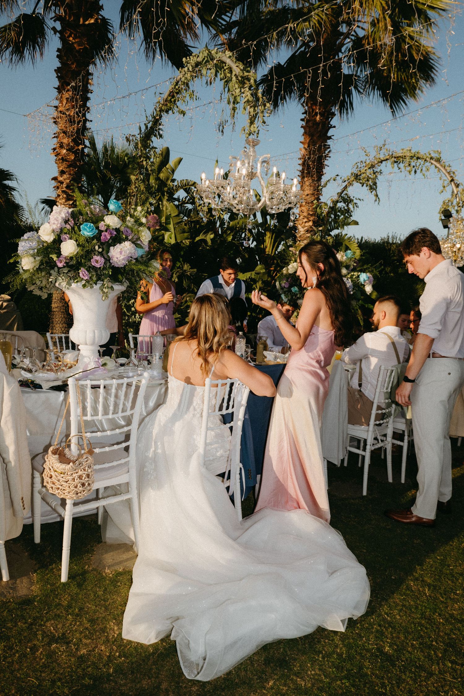 Outdoor wedding reception under palm trees with white chairs and flowing bridal gown movement captured in sequence.