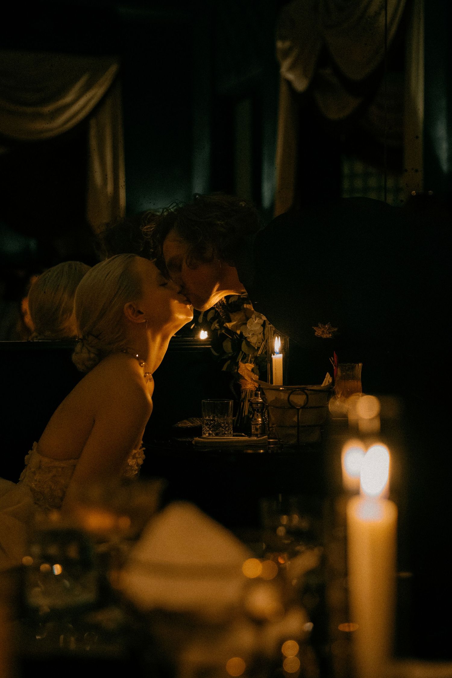 A lit candle glows in a dark room creating a moody and atmospheric ambiance.