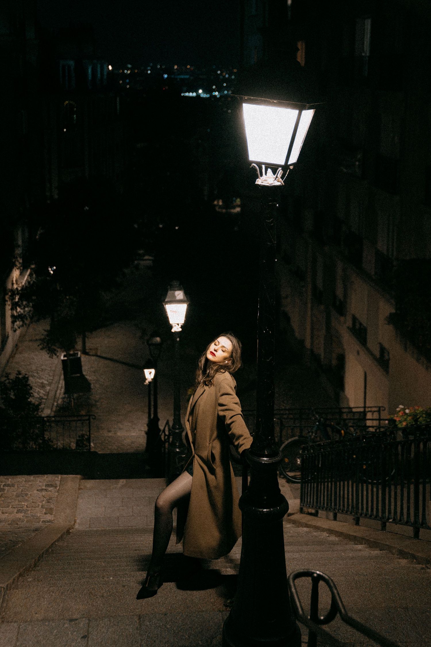 Fashion-inspired night portrait in Montmartre, Paris, editorial destination photography by Studio Reverie under glowing street lamps.