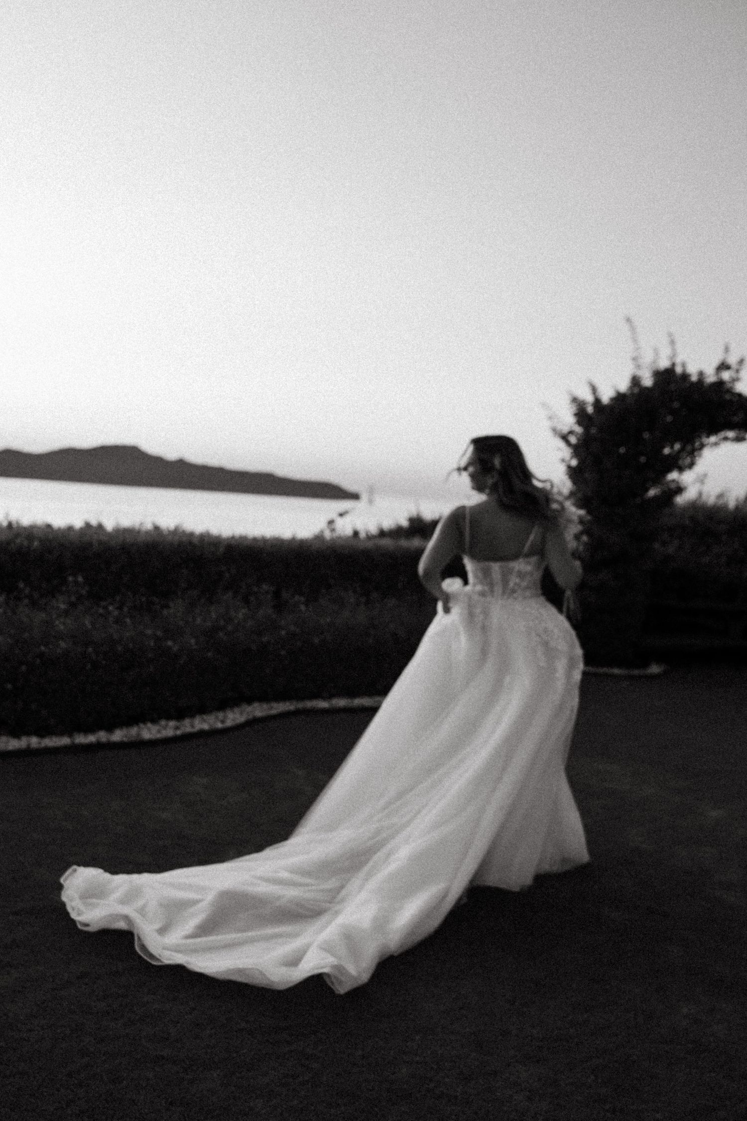 A flowing white wedding dress creates a dramatic silhouette against a black and white landscape.