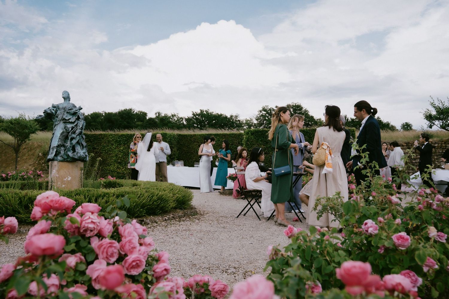 An outdoor wedding celebration set among blooming pink roses and garden scenery.