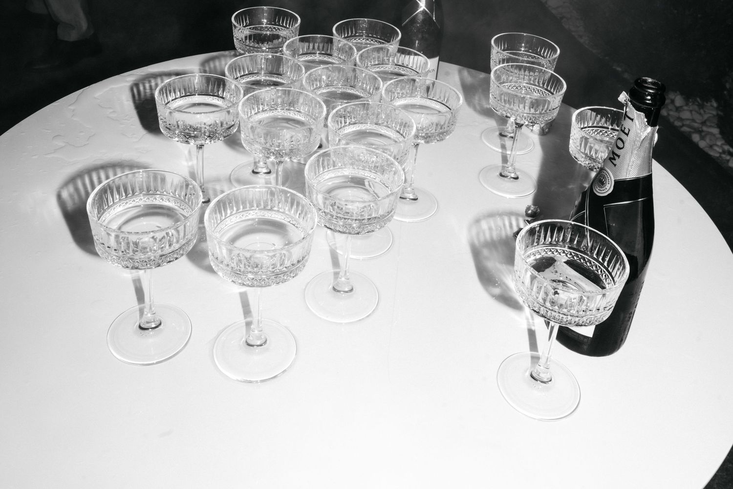 Crystal glassware collection displayed in a row on a white surface with dramatic lighting and shadows.