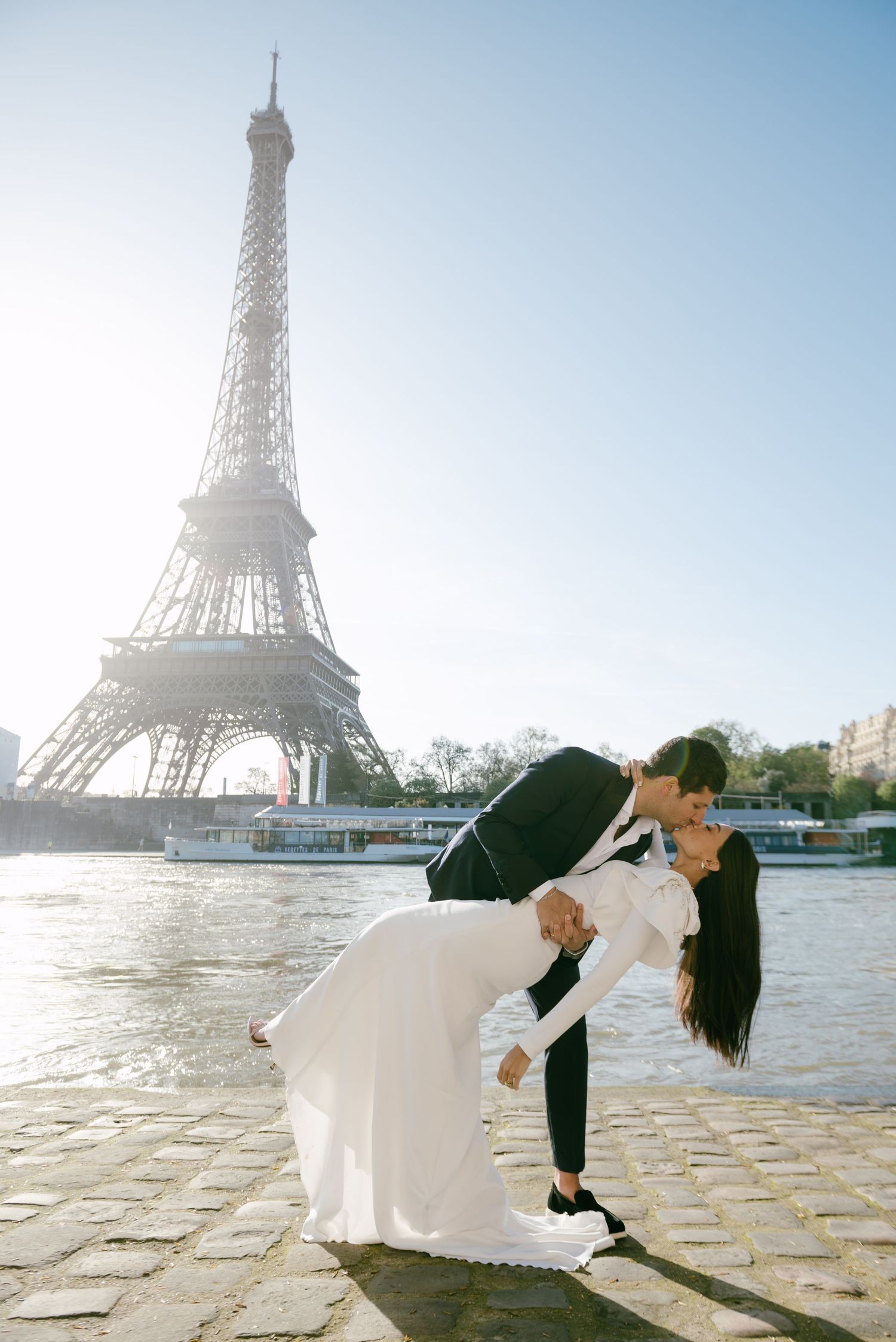 Cinematic Paris couple kiss by the Eiffel Tower, unposed and elegant in bridal fashion, perfect for editorial storytelling.