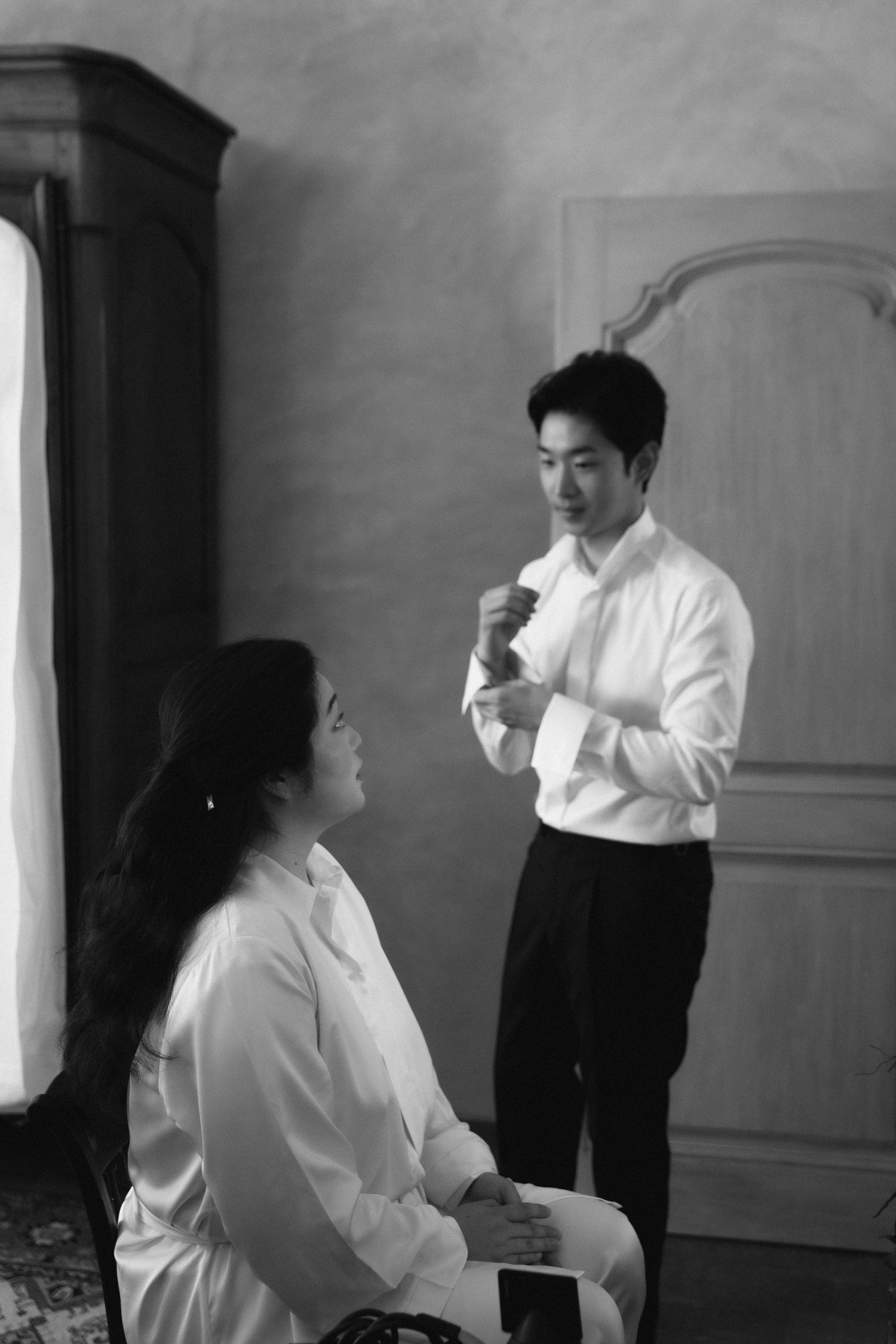 Black and white photo of formal preparation scene with people in white shirts getting ready indoors.