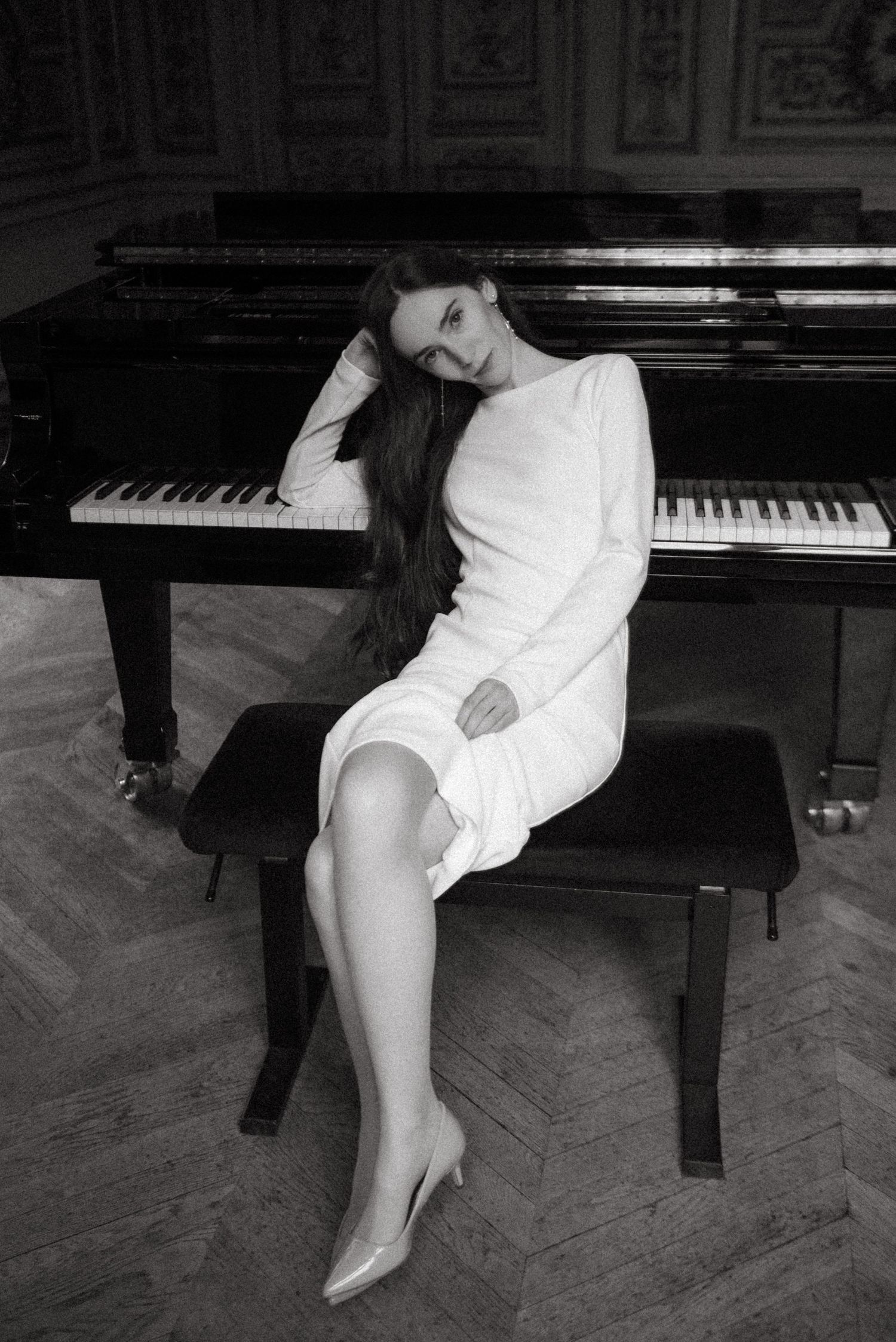 Cinematic black and white artistic portrait in Paris, elegant woman posed beside grand piano in editorial style