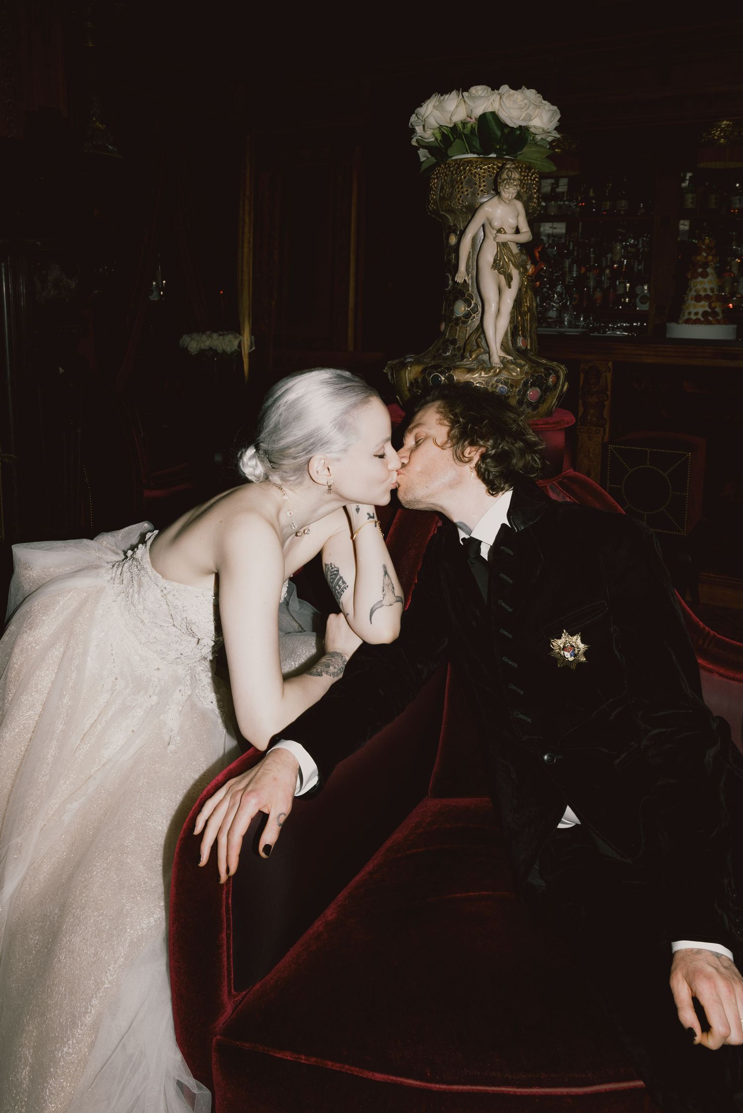 Romantic wedding moment captured in dark theater setting with red velvet seating.
