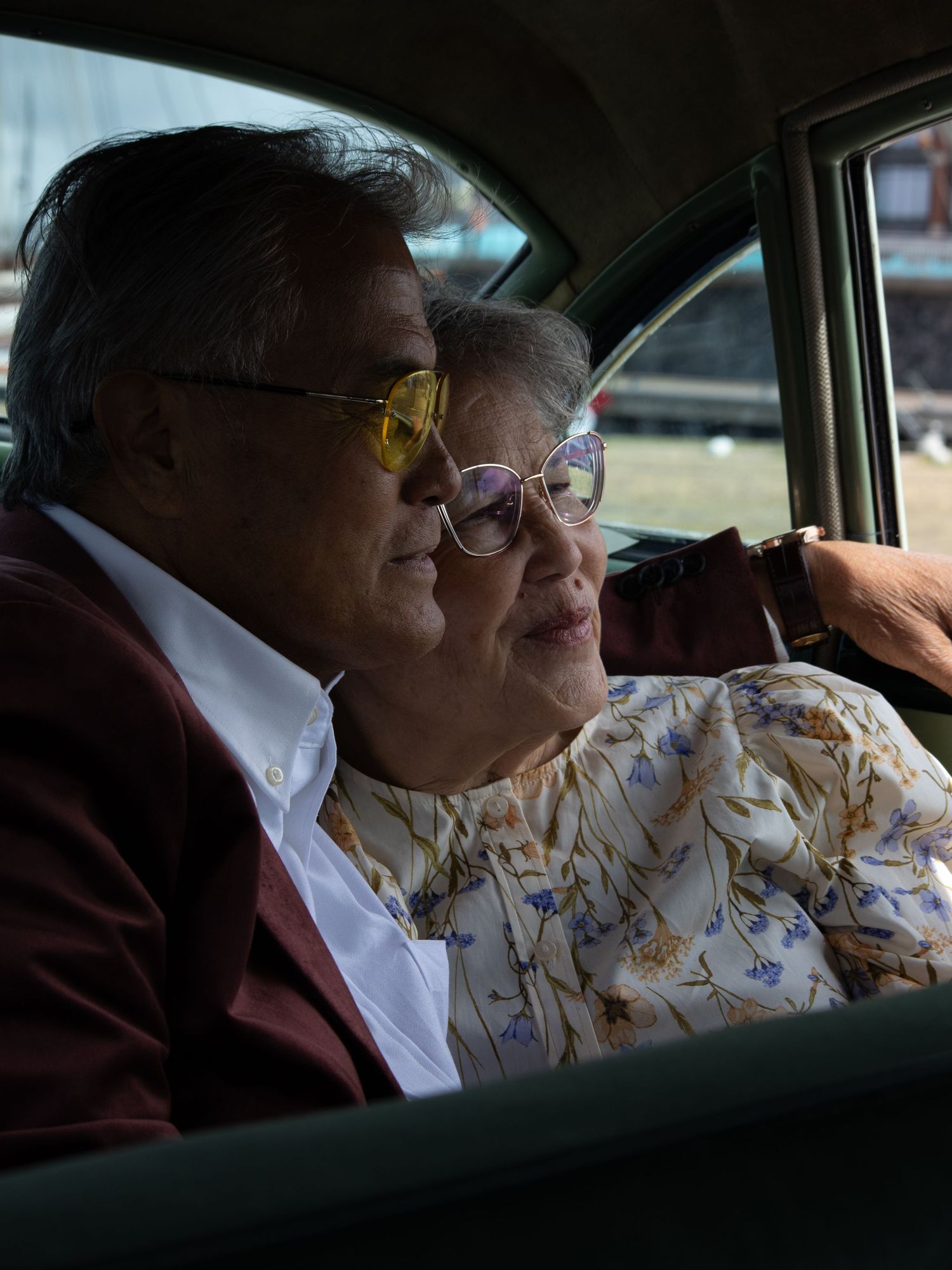 Two people seated in the back of a car wearing formal attire.