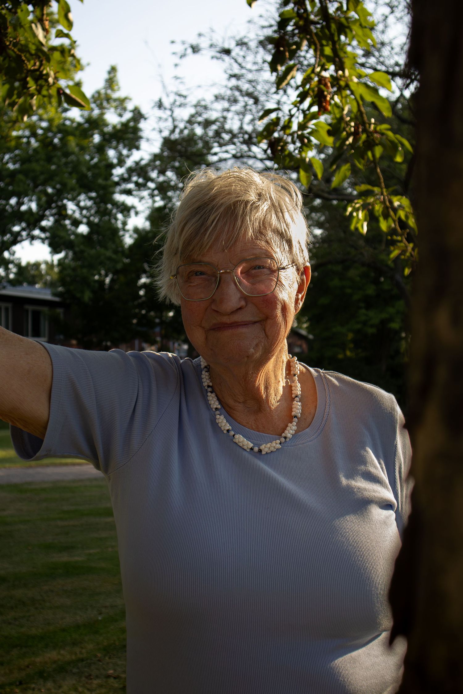 An outdoor portrait showing someone in a light-colored shirt against a backlit natural background.
