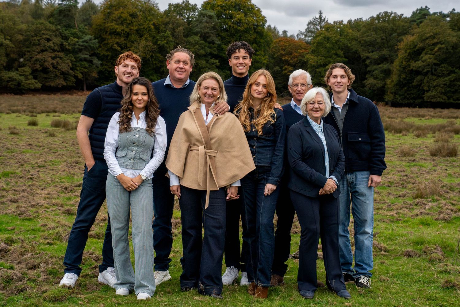 A group of people standing together in a grassy field on a cloudy day.
