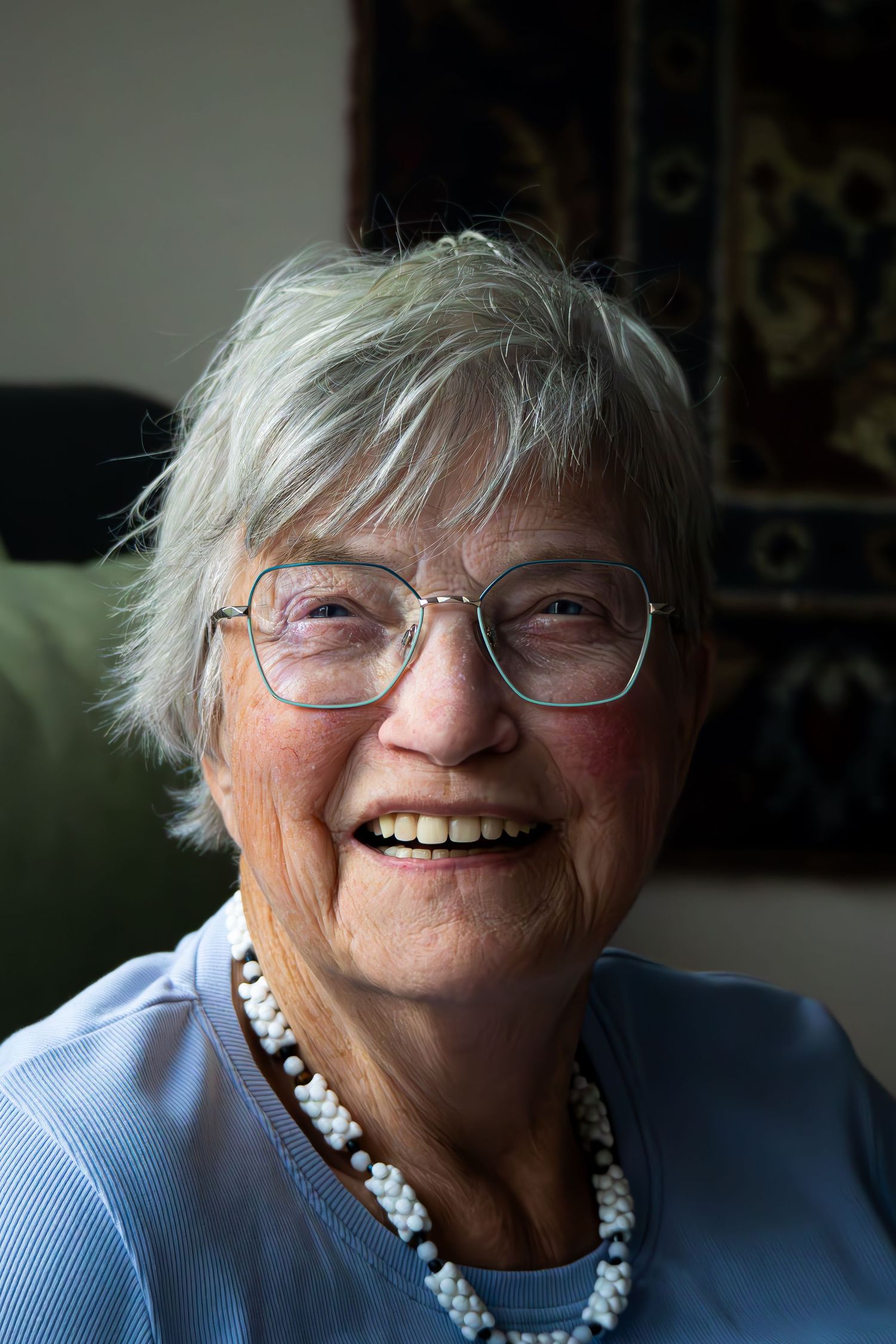 An elderly person wearing glasses and a blue shirt smiles warmly in a series of candid shots.