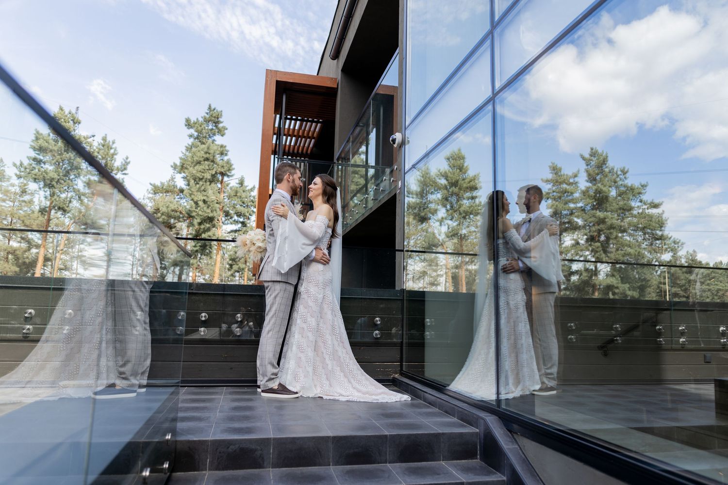 Architectural wedding photos showing reflections in glass windows of a modern building.