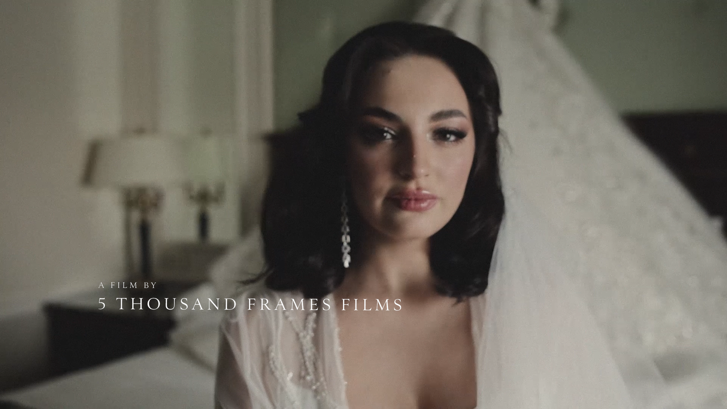 Elegant bride in white veil and drop earrings poses in soft light, film by 5 Thousand Frames Films.