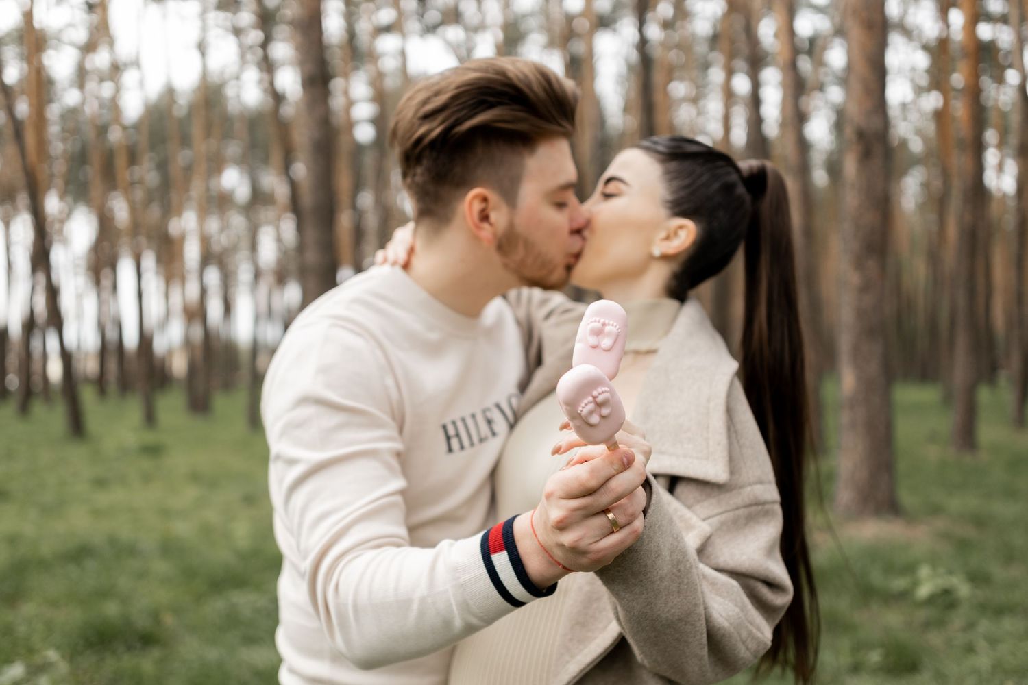 Couples pose together in a wooded area during a gender reveal photoshoot.