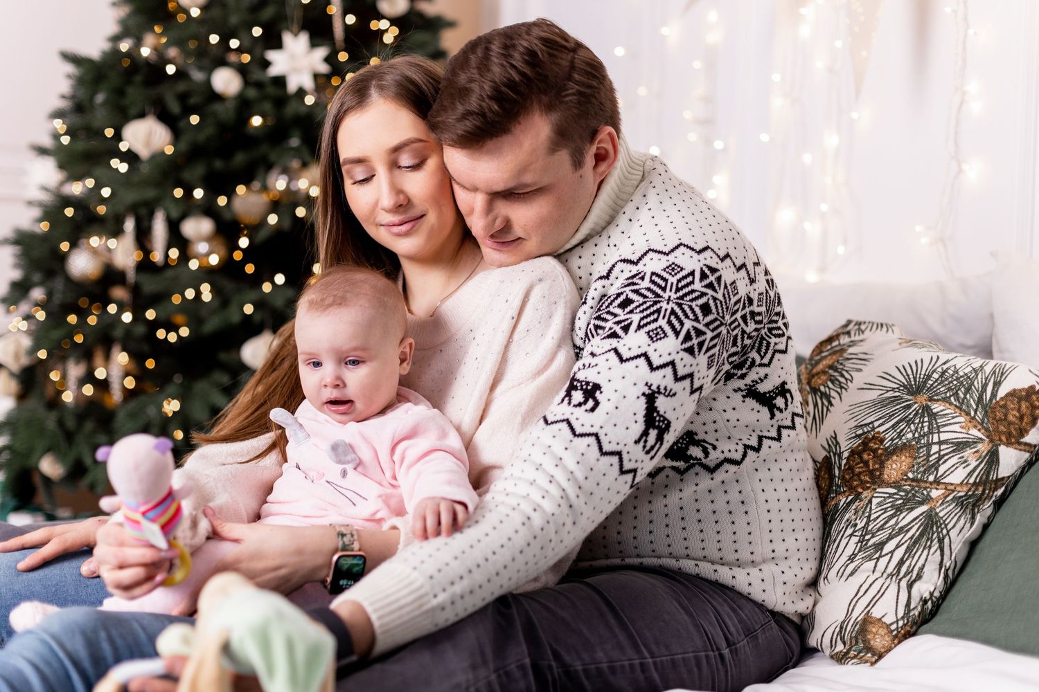 Relaxed family portrait on velvet couch with Nordic winter sweaters and holiday decor.