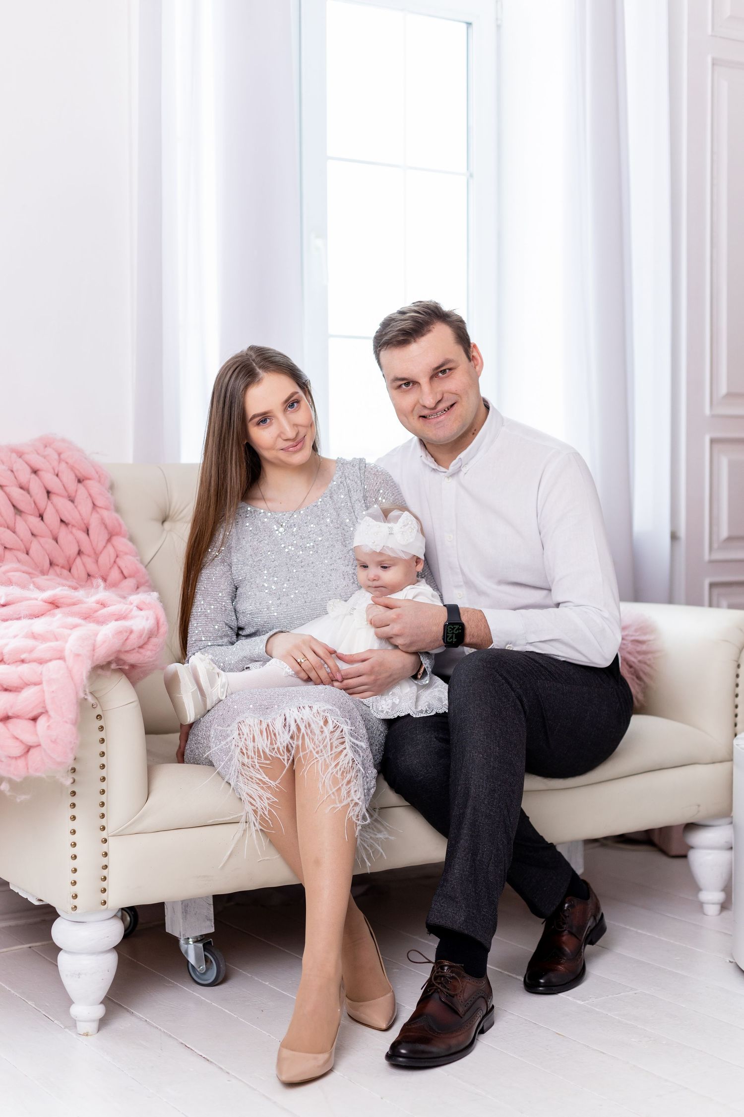 Family relaxes on pink tufted sofa during elegant holiday photoshoot.