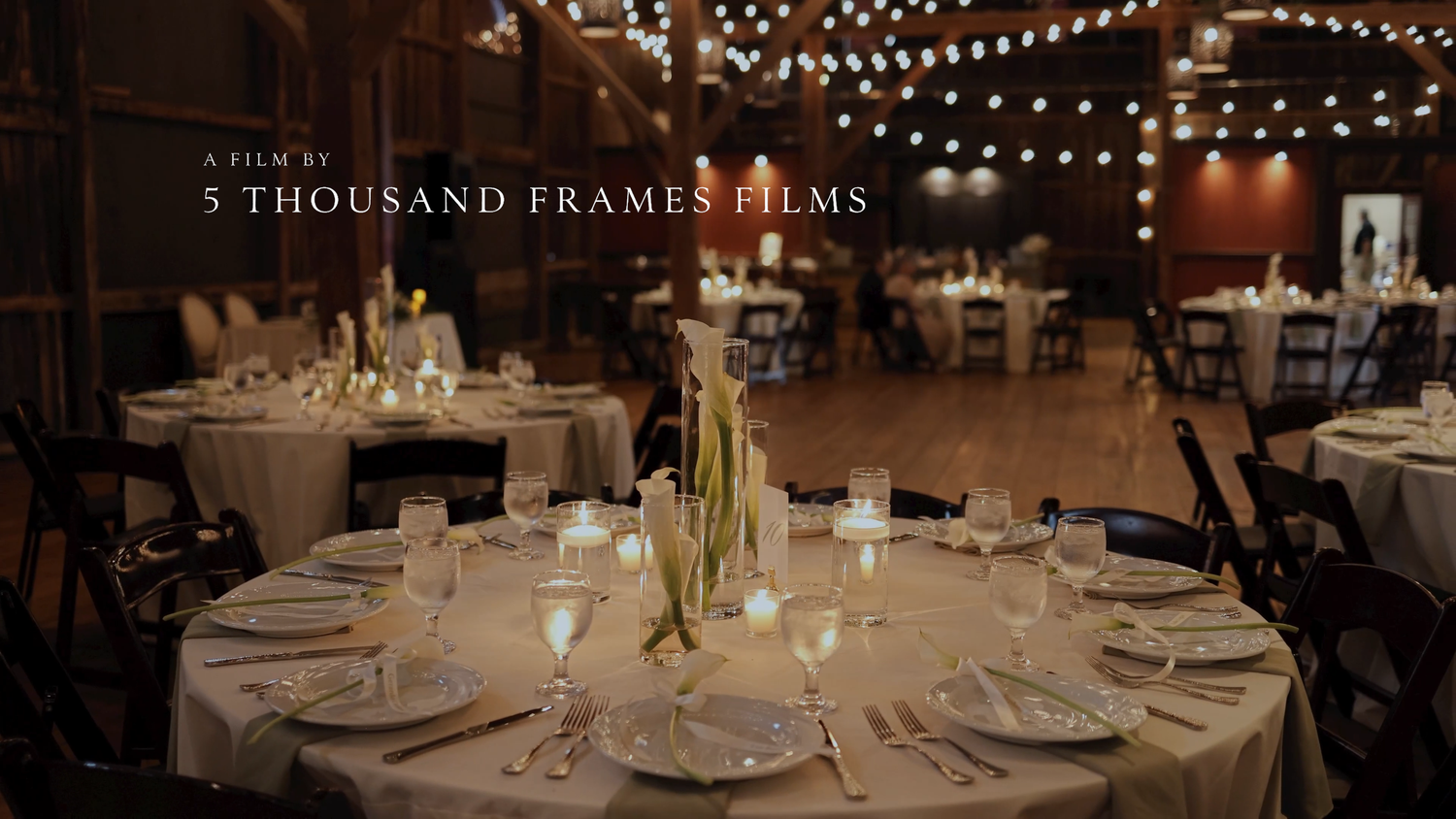 Elegant wedding reception venue with round tables, candlelight, and string lights by 5 Thousand Frames Films.