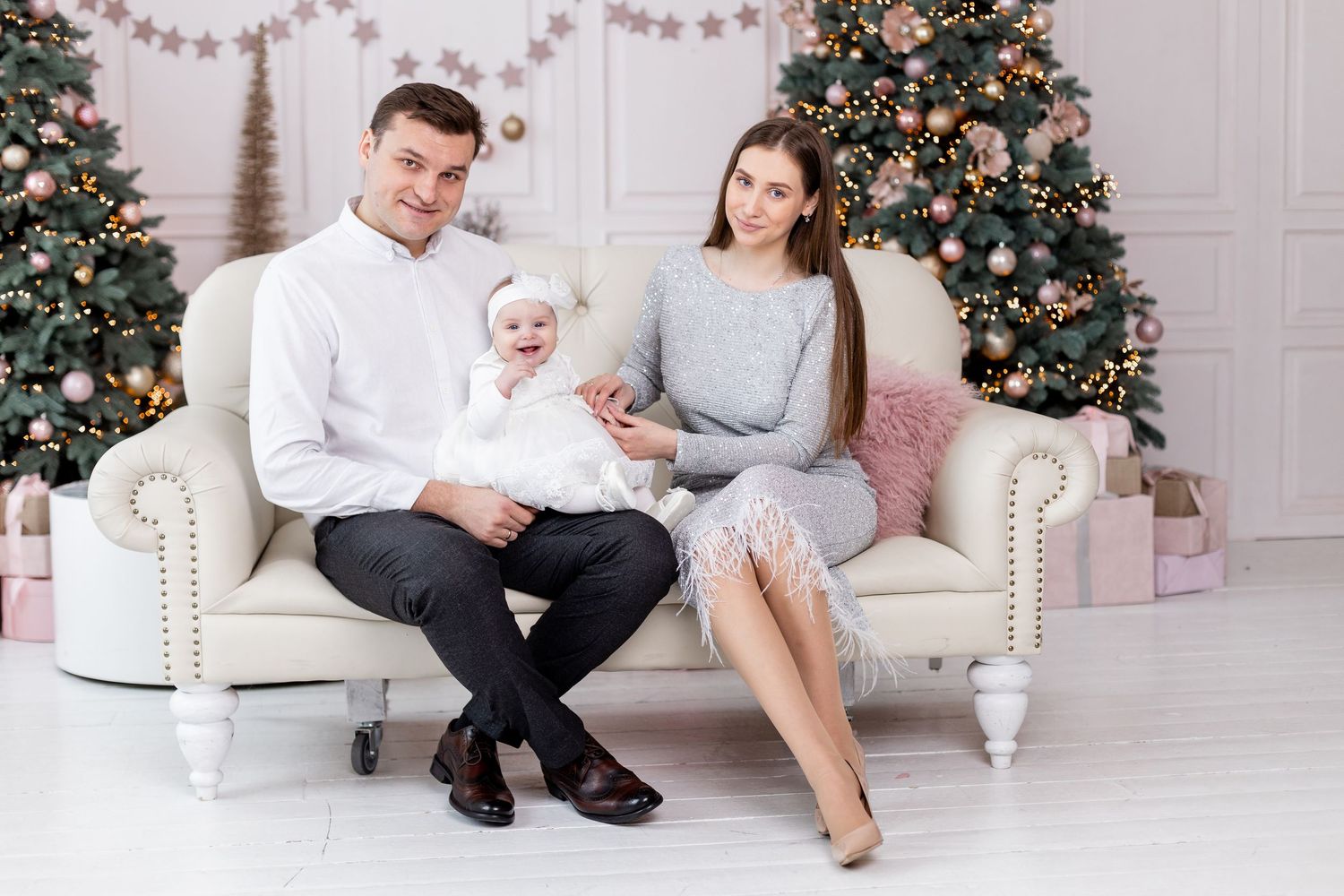 Family sitting on white couch near Christmas tree with decorative star garland.