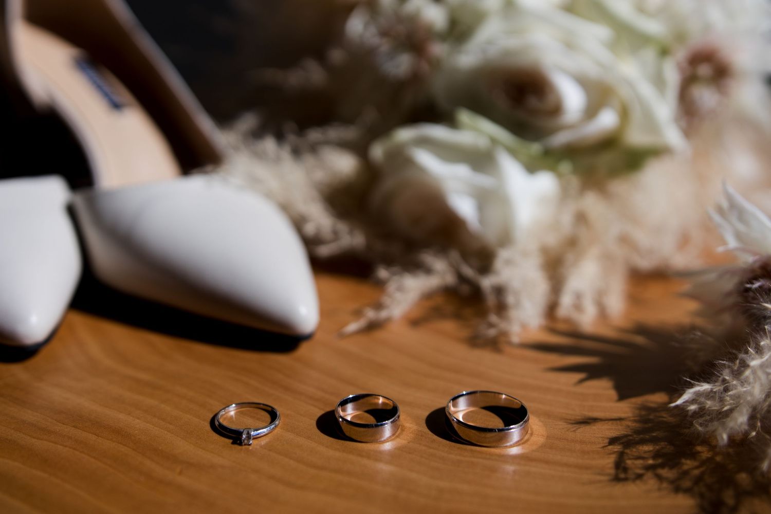 Wedding rings and decorative elements arranged on a wooden surface.
