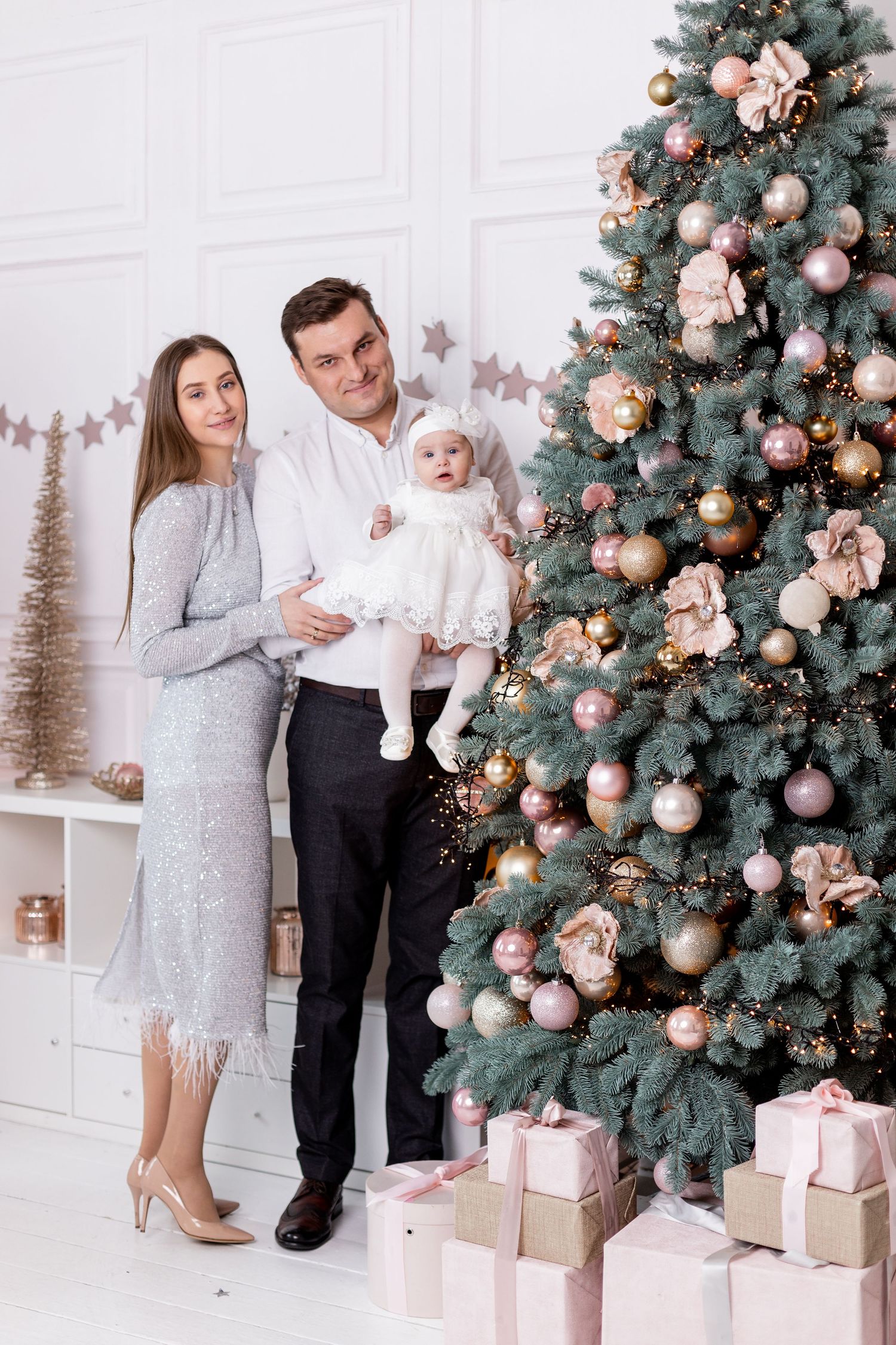 Elegant Christmas portrait with decorated tree, pink ornaments, and wrapped presents.
