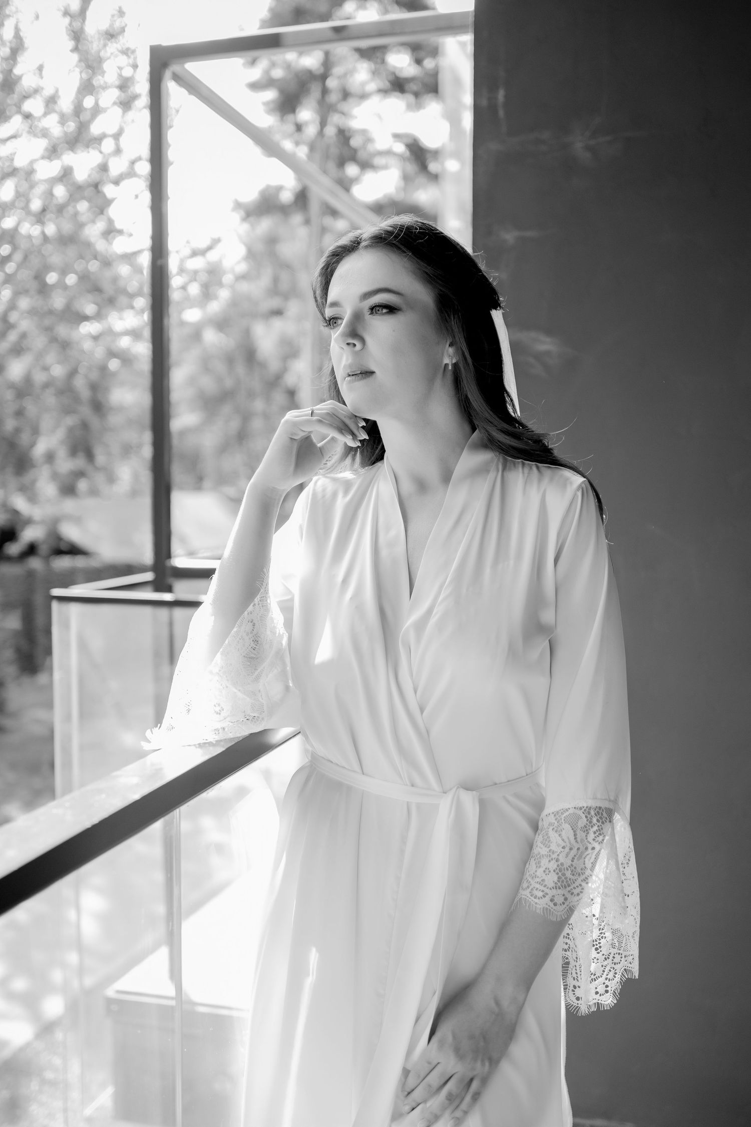 Ethereal bridal morning preparation photos in white robe by window.