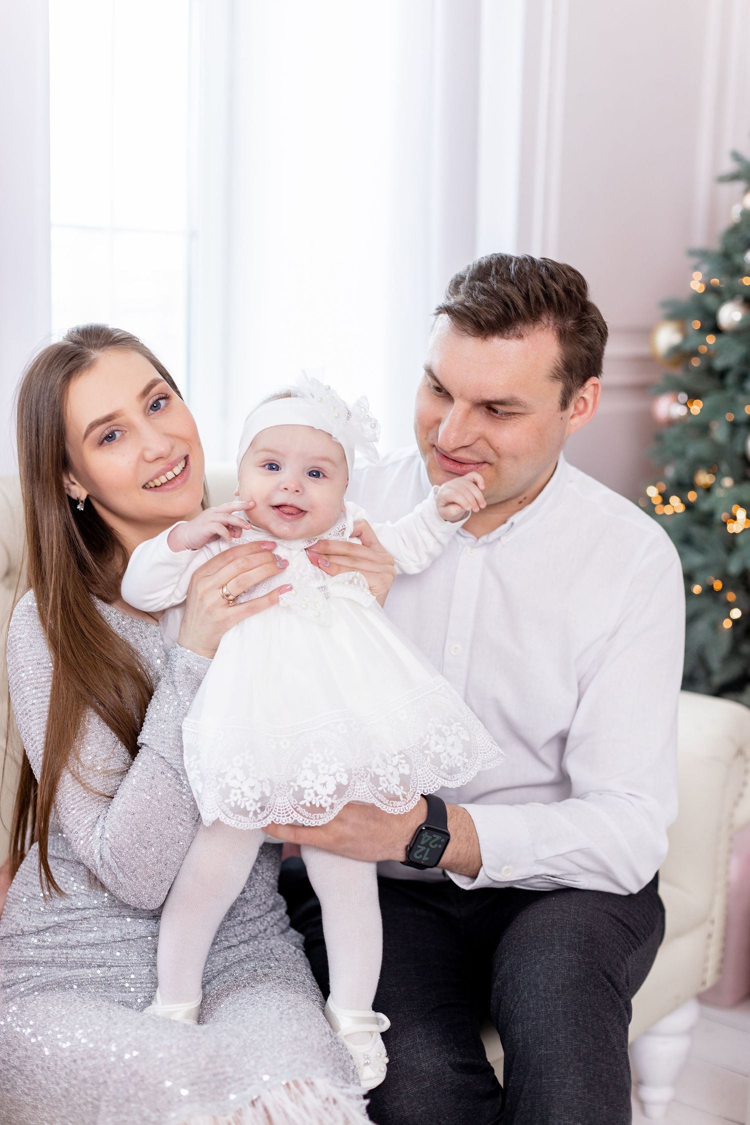 Playful holiday family portraits with white and silver Christmas decor.