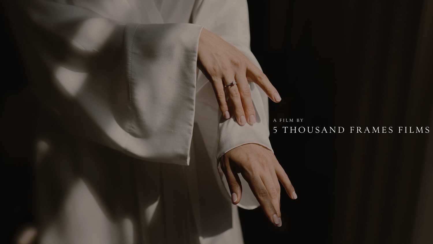 Elegant bride in white silk gown with gold wedding ring, cinematic film still by 5 Thousand Frames Films.