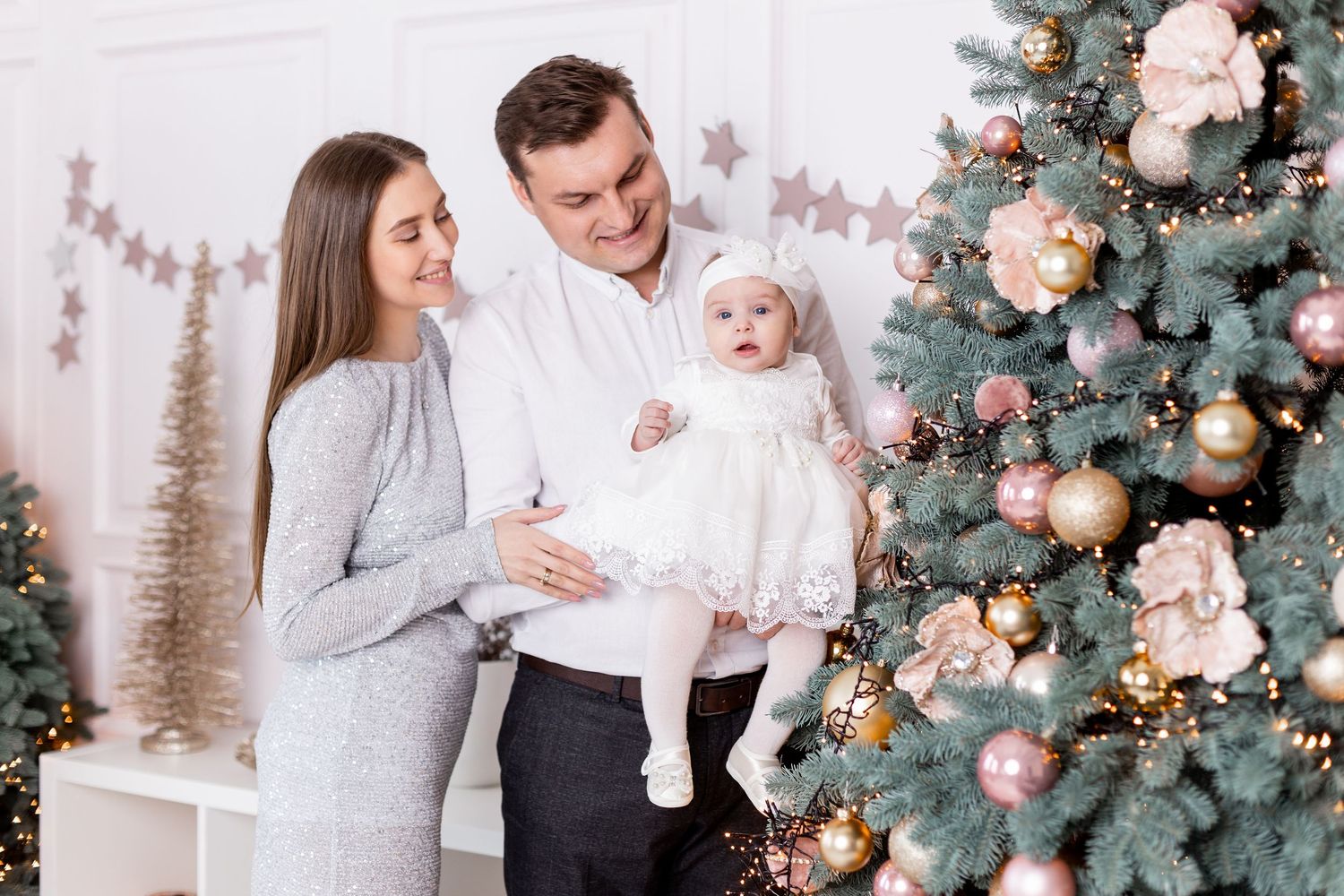 Holiday family portrait session with sparkly grey dress and white decorations near Christmas tree.