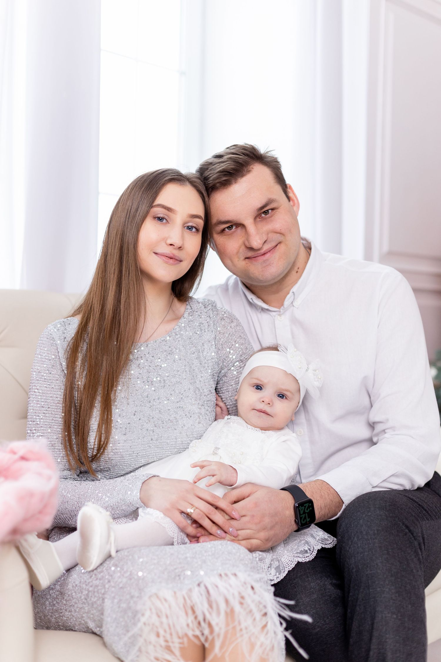 Family lounges on cream sofa during elegant holiday portrait session.
