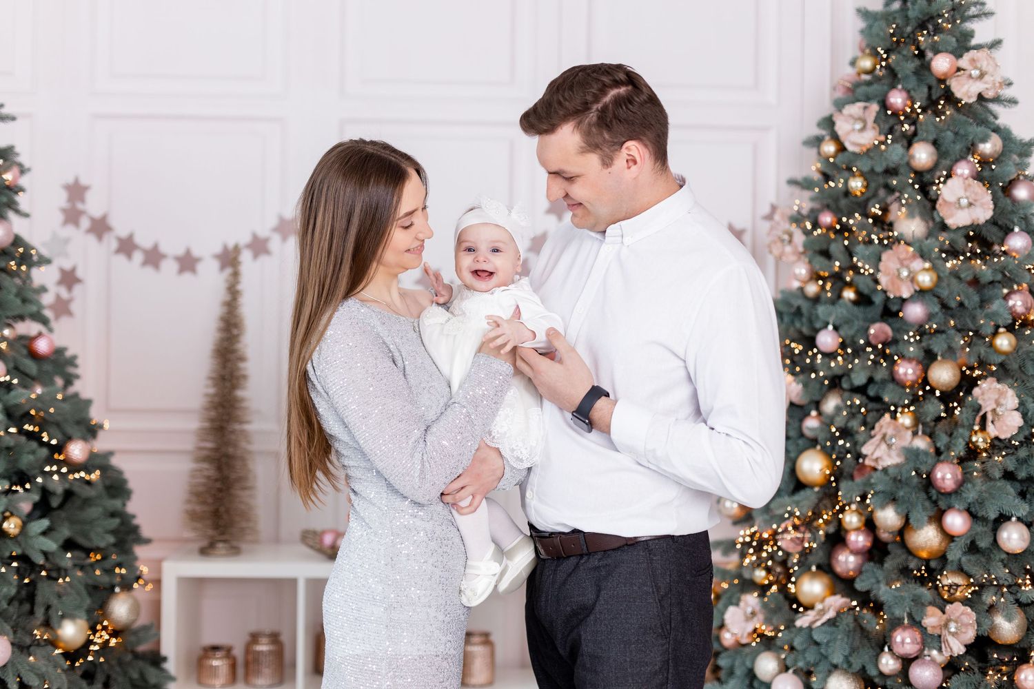 Candid family moments captured by decorated Christmas tree with pink and silver theme.