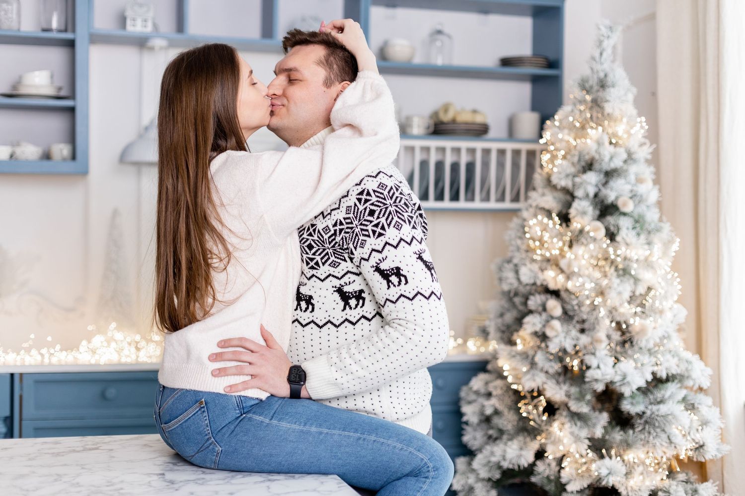 Cozy holiday scene with decorated Christmas tree and couple in matching winter attire.