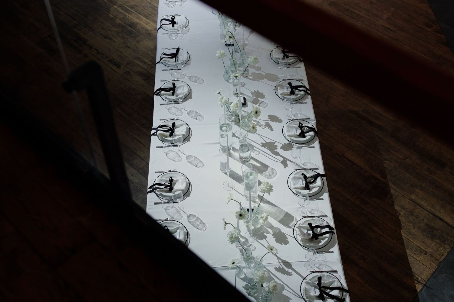 White decorative table runner with black logo prints displayed on a wooden table in natural lighting.