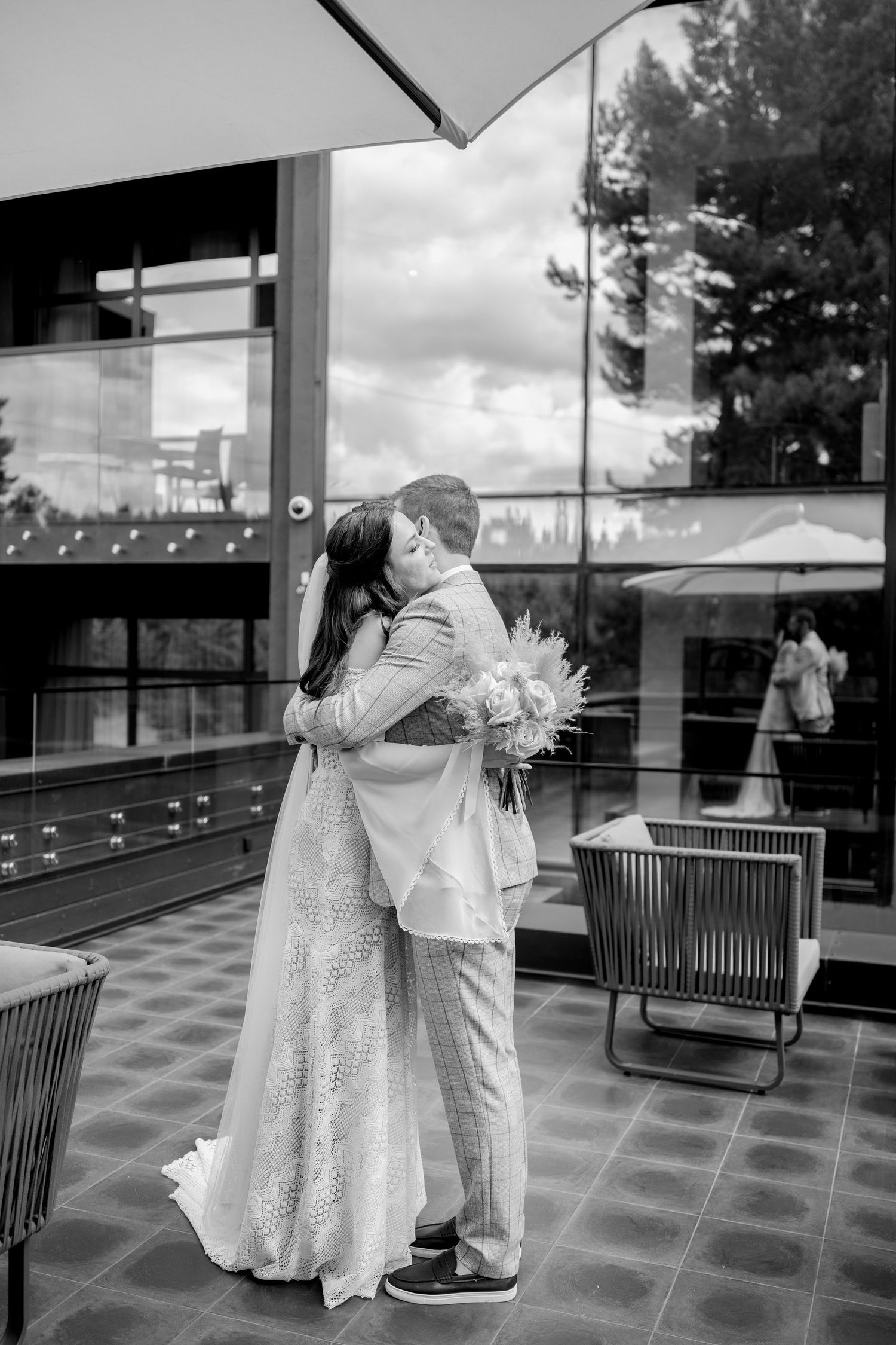 Black and white wedding photo showing an intimate embrace on a modern patio.