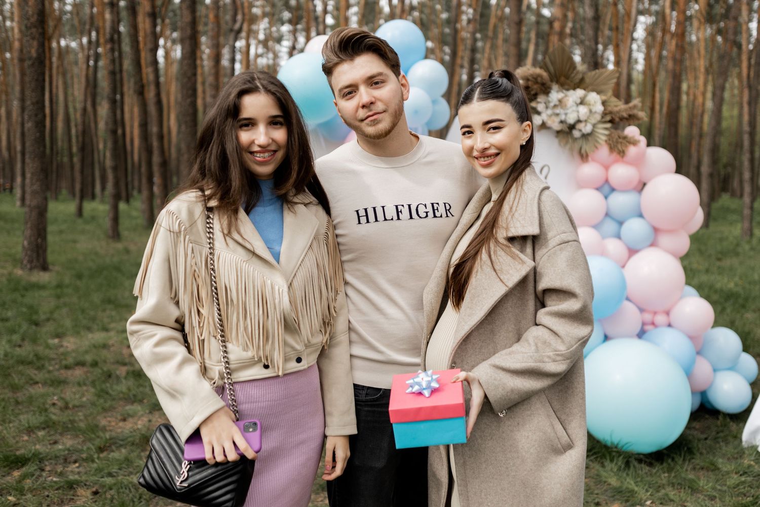 Gender reveal party guests celebrating with gifts and pastel decorations.