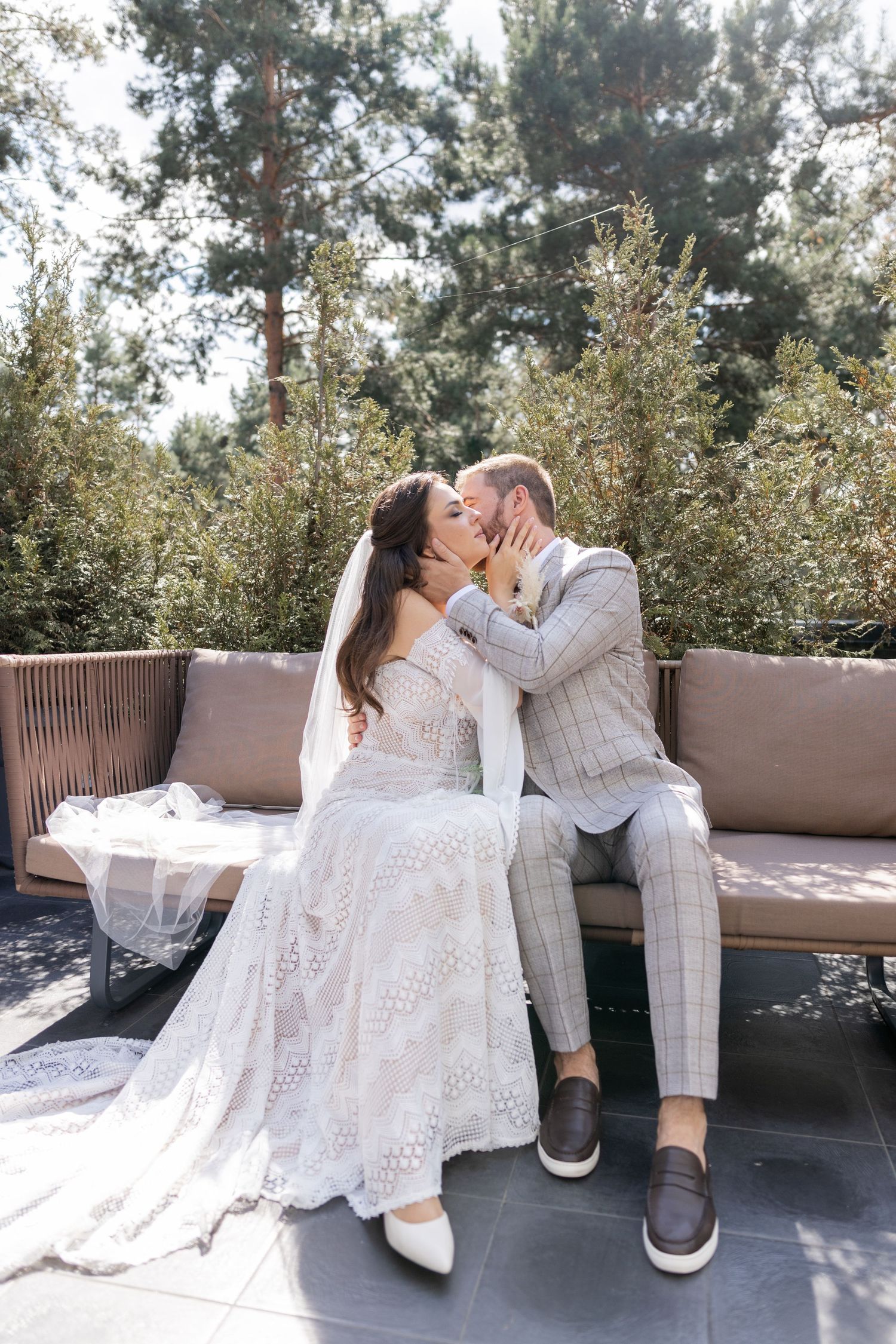 Romantic wedding photos of a couple lounging on a bench in an outdoor setting.