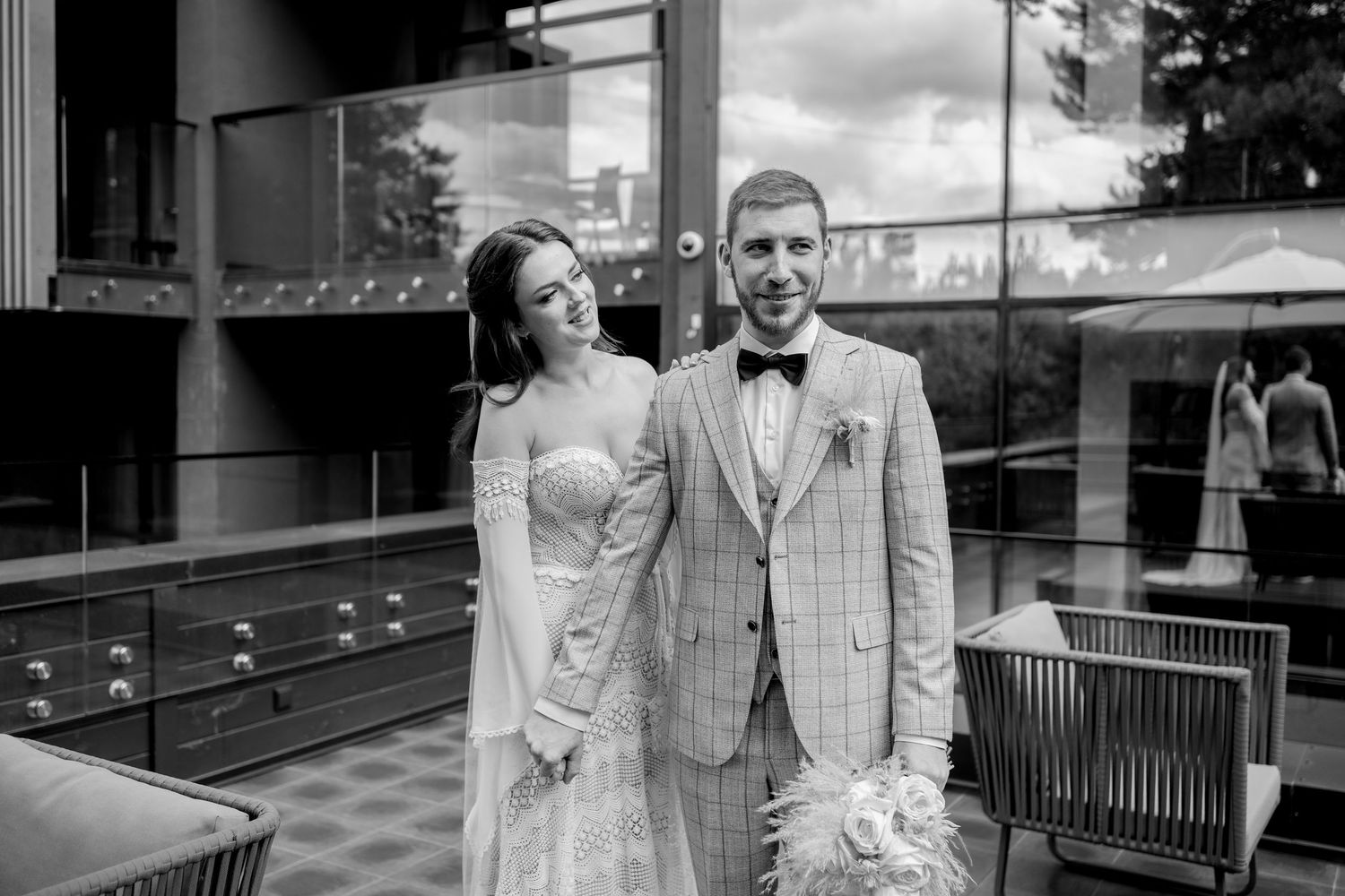 A romantic first look moment captured on a contemporary outdoor terrace with wooden benches.