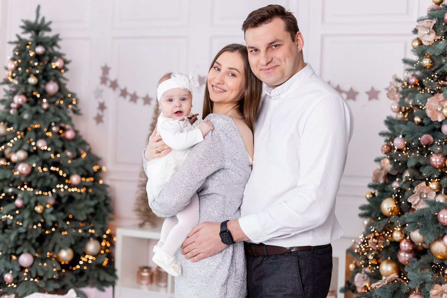 Holiday portrait series with Christmas tree and pink and silver decorations in white room.