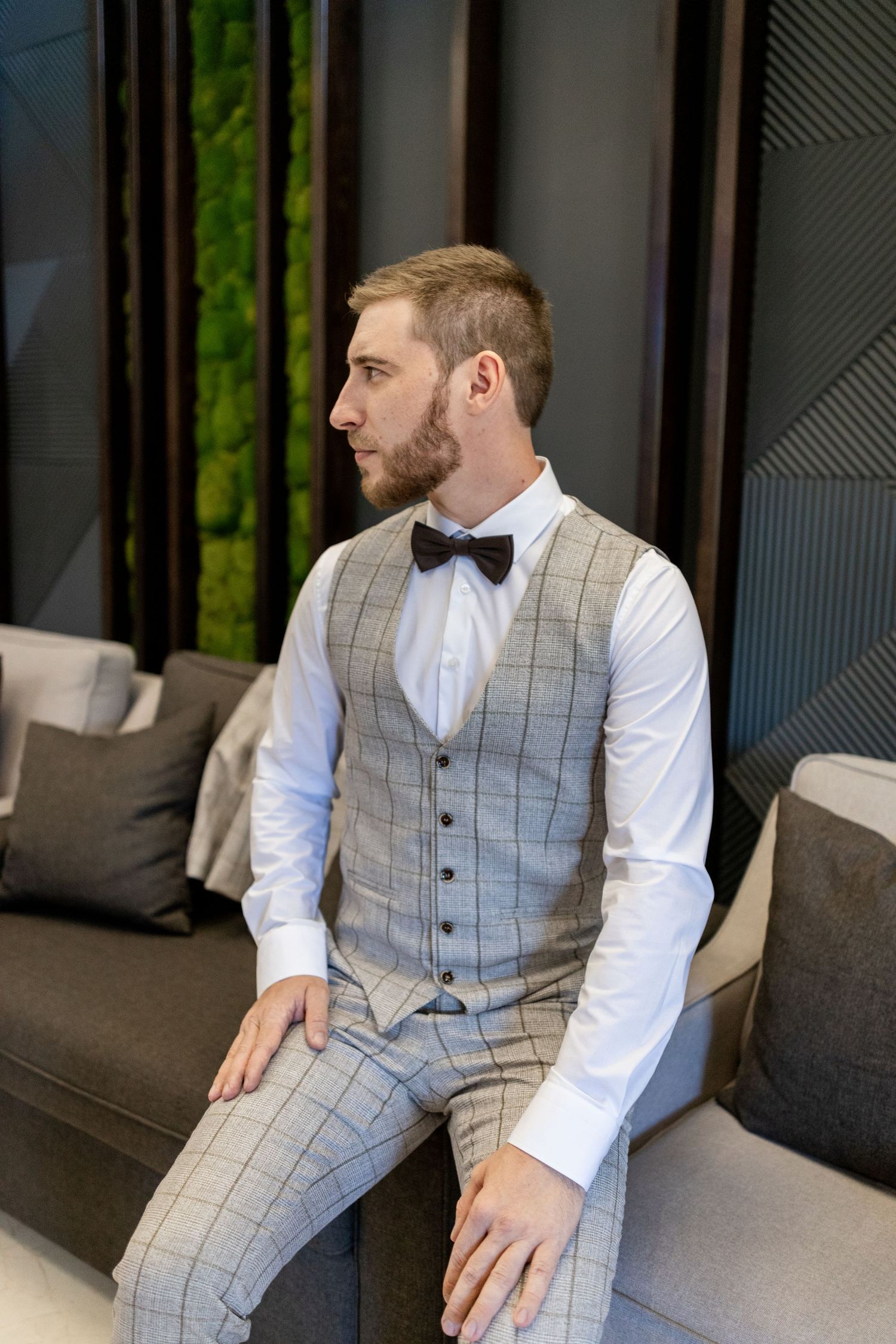 Formal gray checkered vest and white shirt combination captured in modern lounge setting.