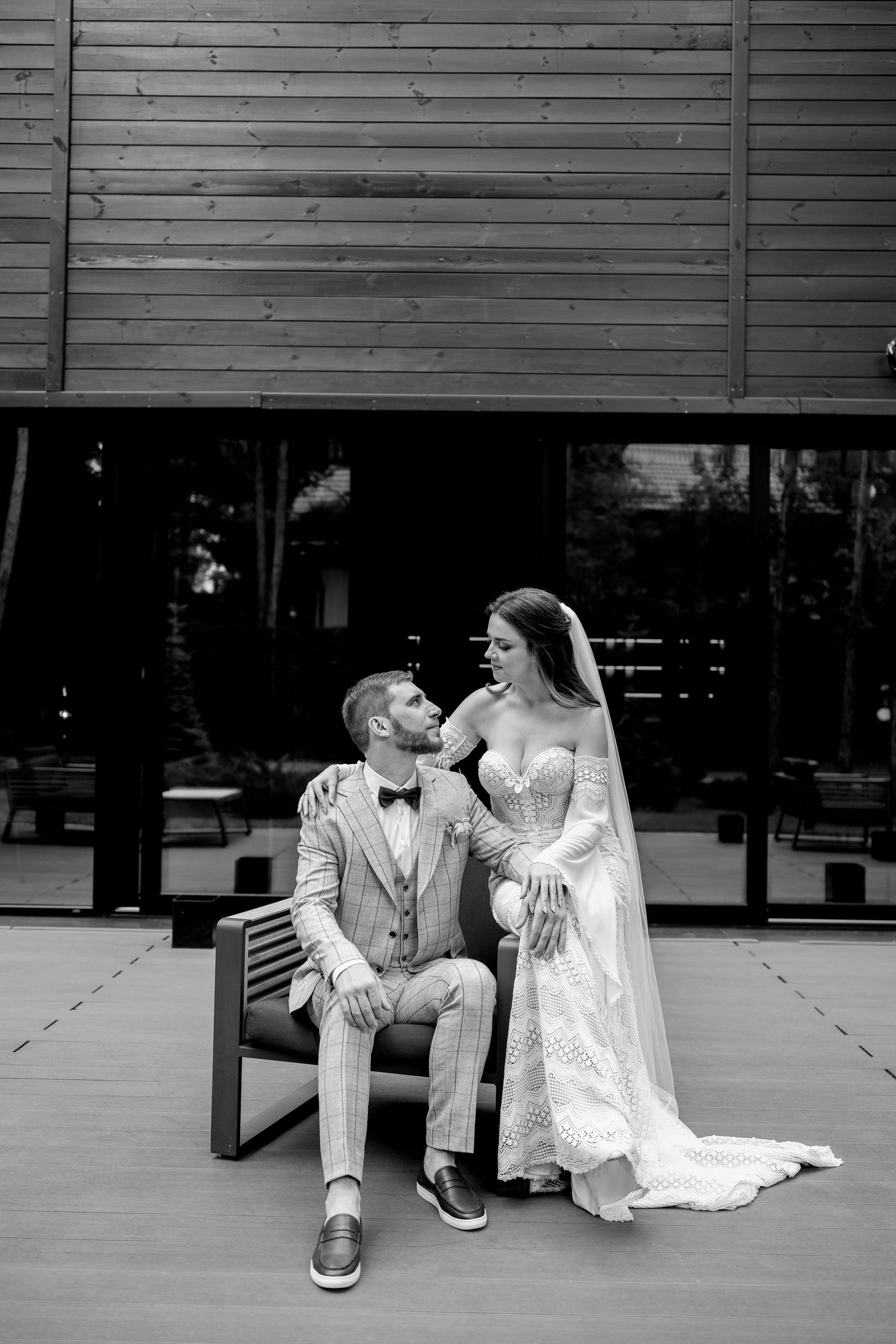 Black and white wedding photos of couple sitting and interacting on outdoor bench.