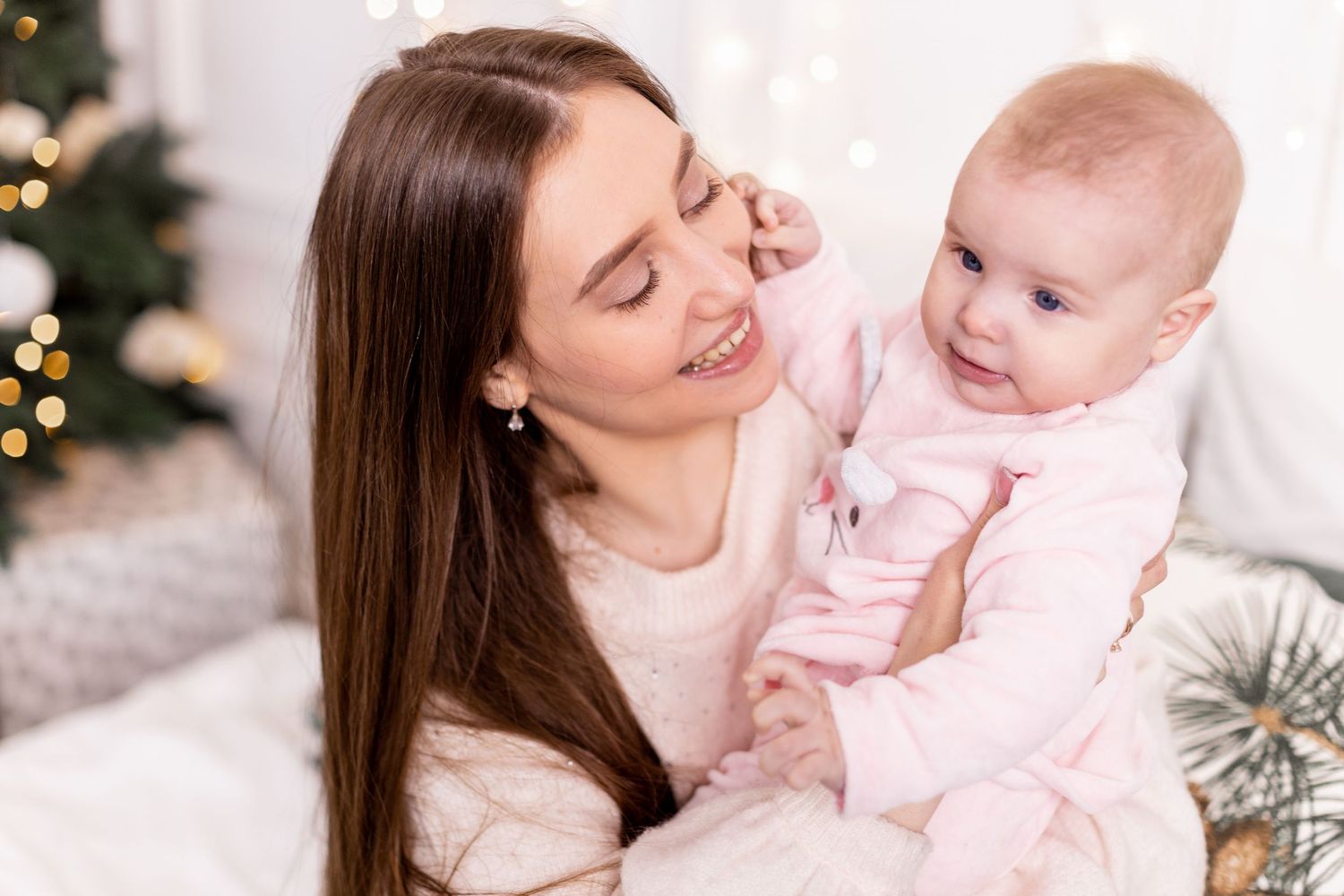 Joyful winter family portraits with baby in pink against festive holiday backdrop.