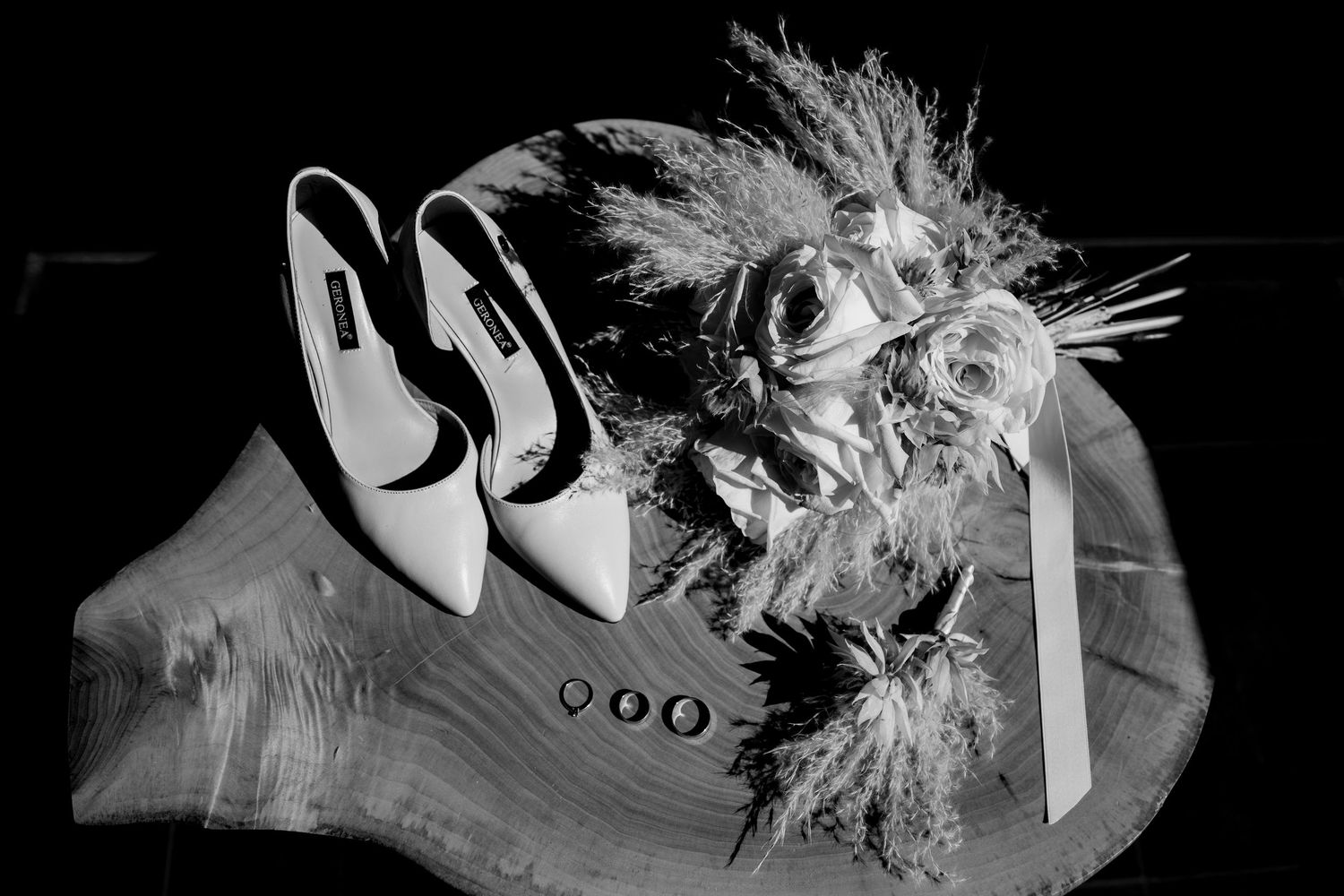 Artistic black and white photo of wedding accessories and dried flowers.
