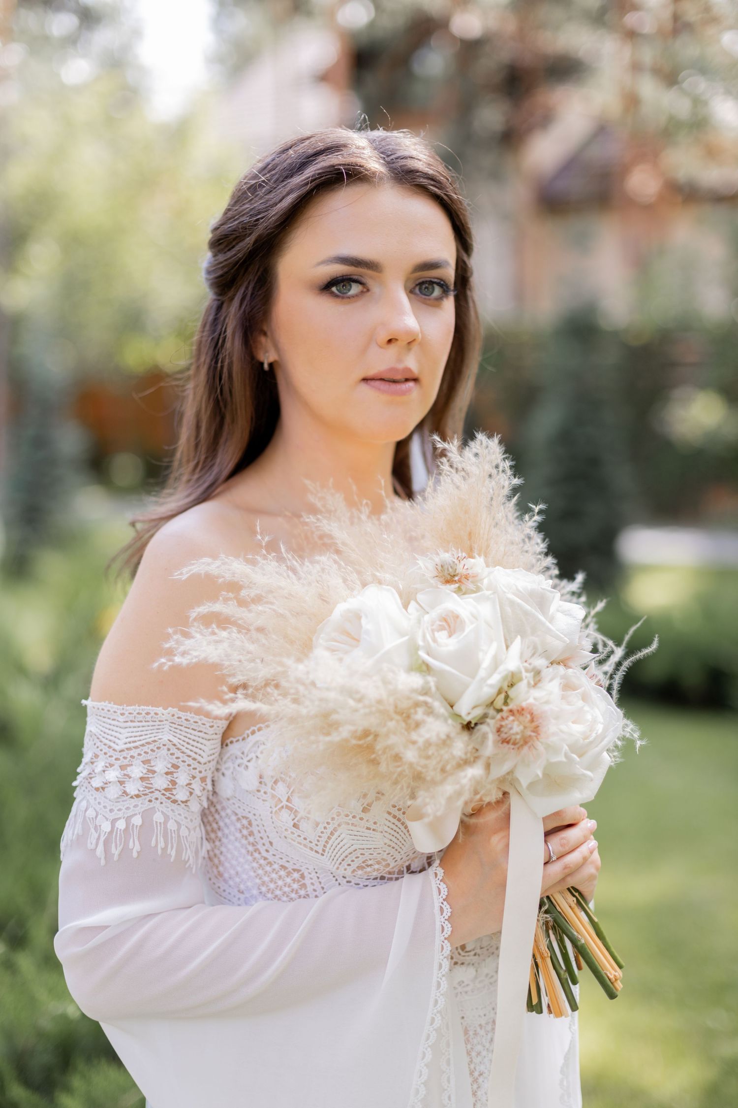 Bride holds a beautiful dried flower bouquet against natural outdoor backdrop.