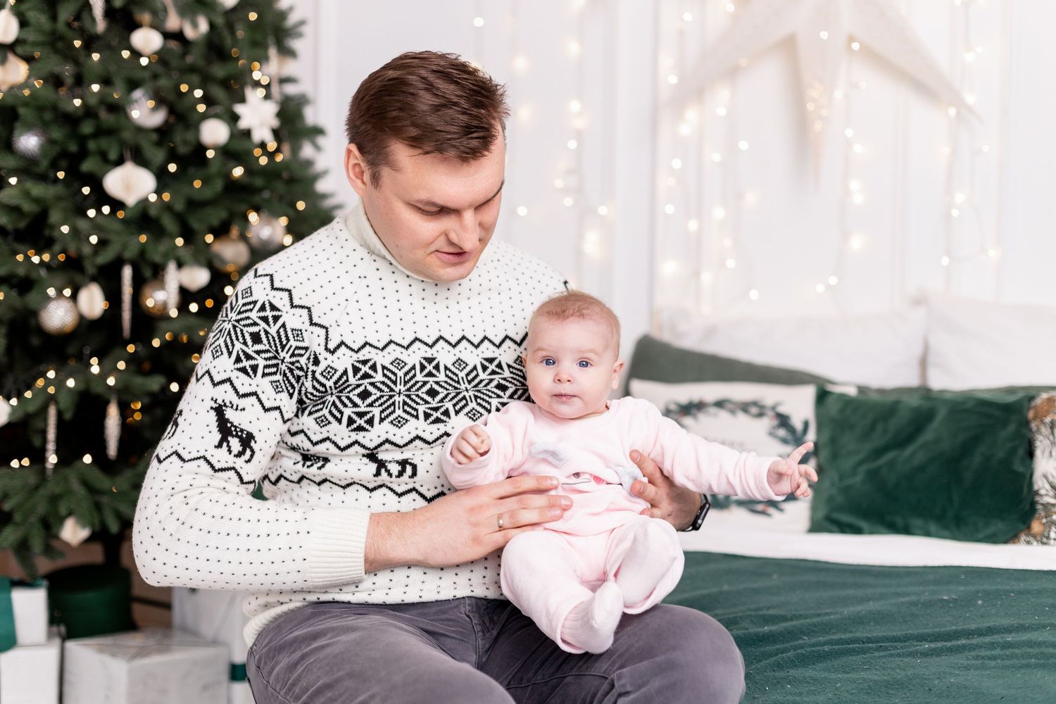 Family relaxing on green velvet couch during holiday photoshoot with decorated tree.