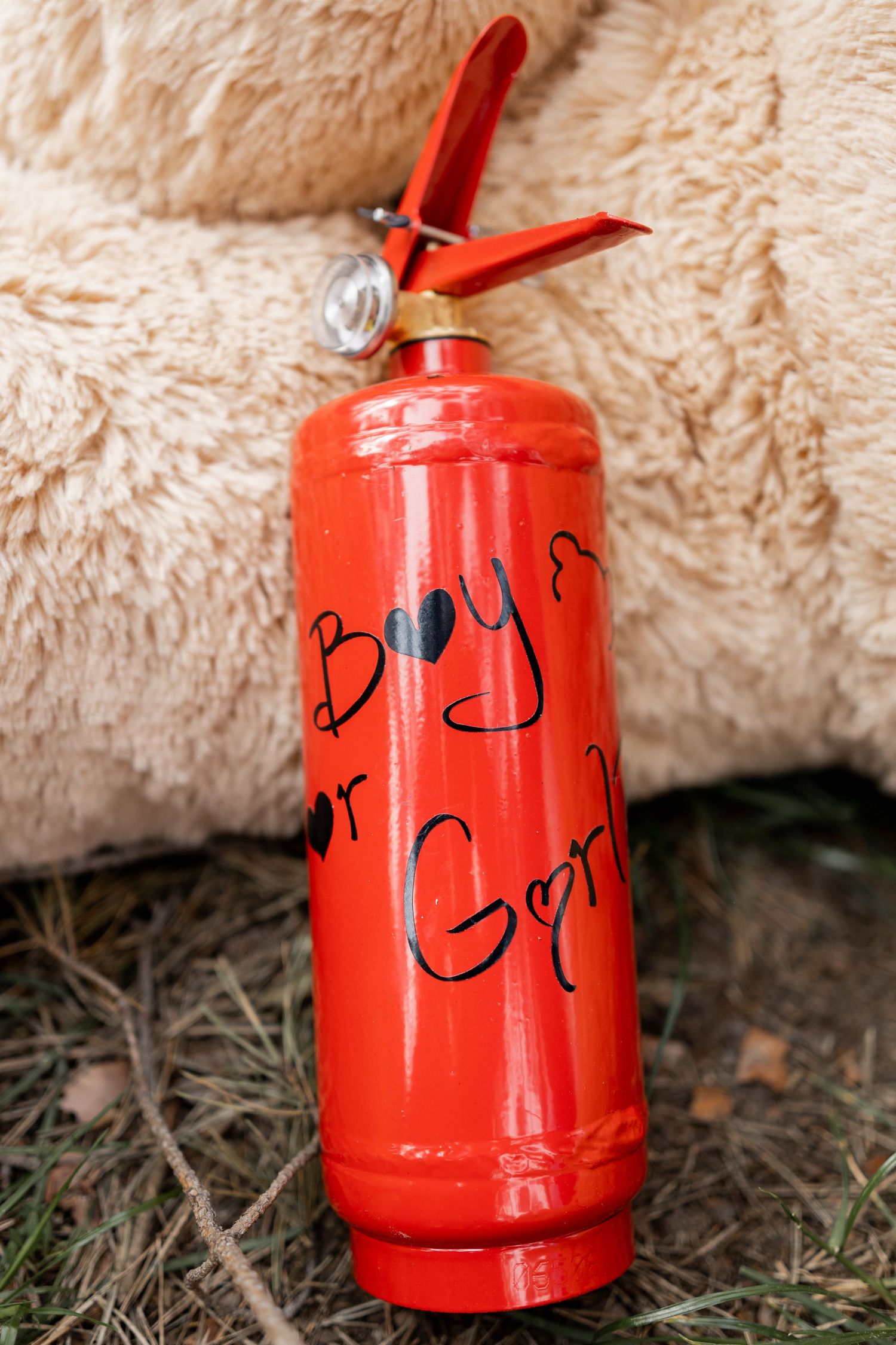 Red canister with writing sits on fluffy beige surface outdoors.