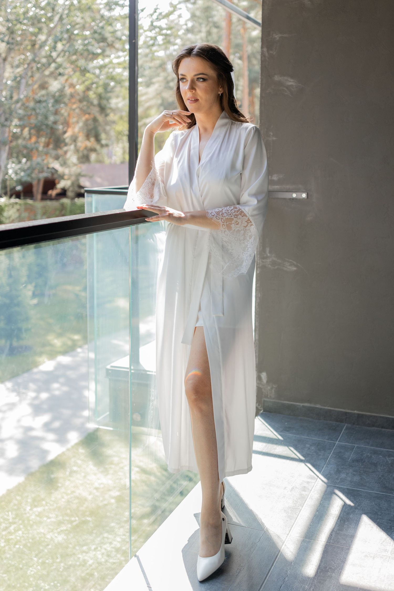 Elegant white bridal robe captured in natural light on modern balcony setting.