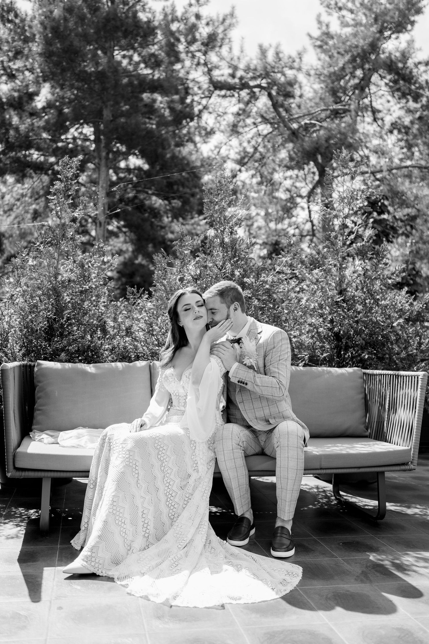 Black and white wedding photos on an outdoor terrace with natural greenery in background.