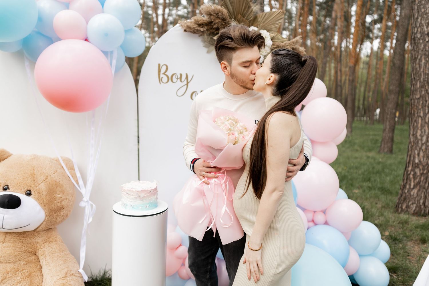 Forest gender reveal celebration with pink and blue balloon arrangements.