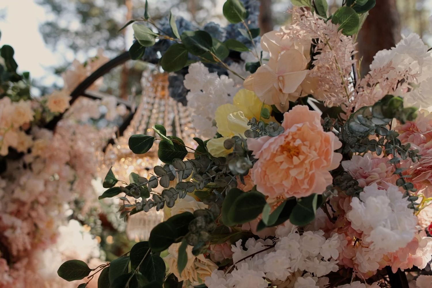 Elegant wedding floral arrangement featuring soft pink peonies, white blooms, and eucalyptus greenery on a decorative arch.