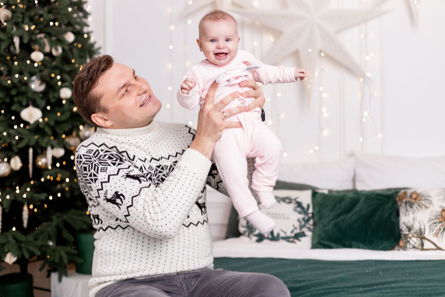 Candid family moments on couch with Christmas tree and white winter decorations.
