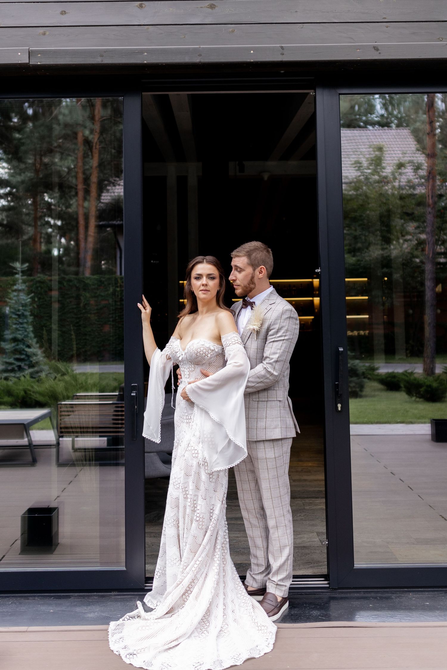 Romantic wedding photoshoot featuring a couple in white attire dancing and embracing outside a modern building.