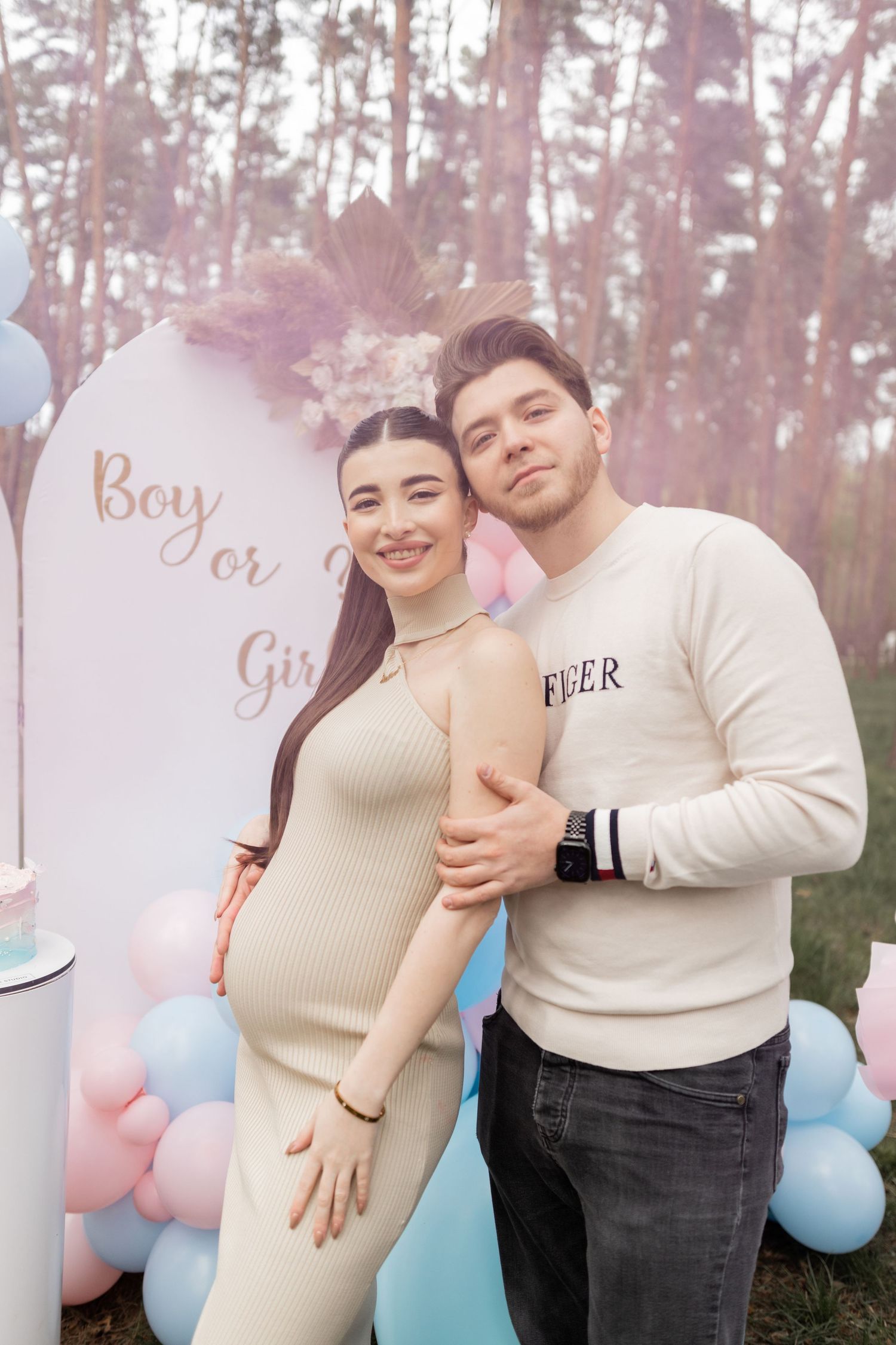 Gender reveal party in wooded setting with pink and blue balloon decorations.